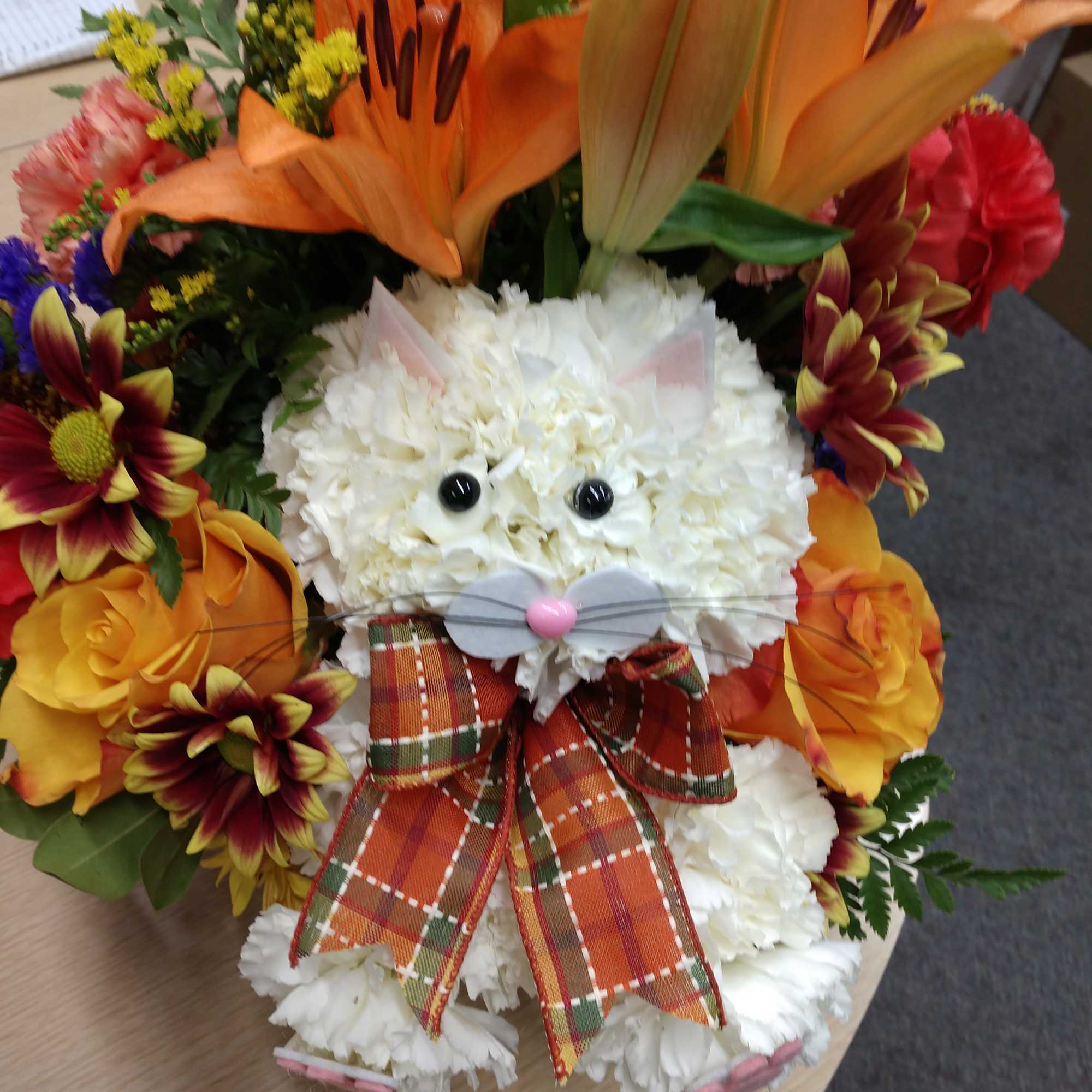 Flower arrangement shaped like a cat with orange lilies and roses