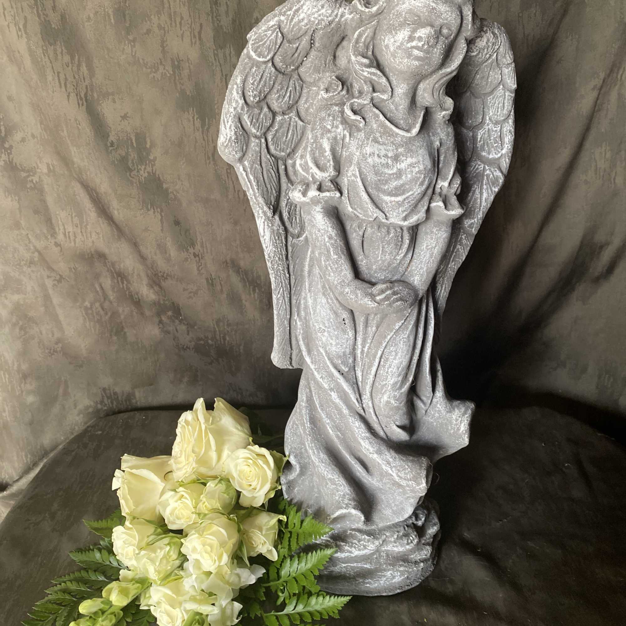Silver angel statue with a small bouquet of white roses and greenery
