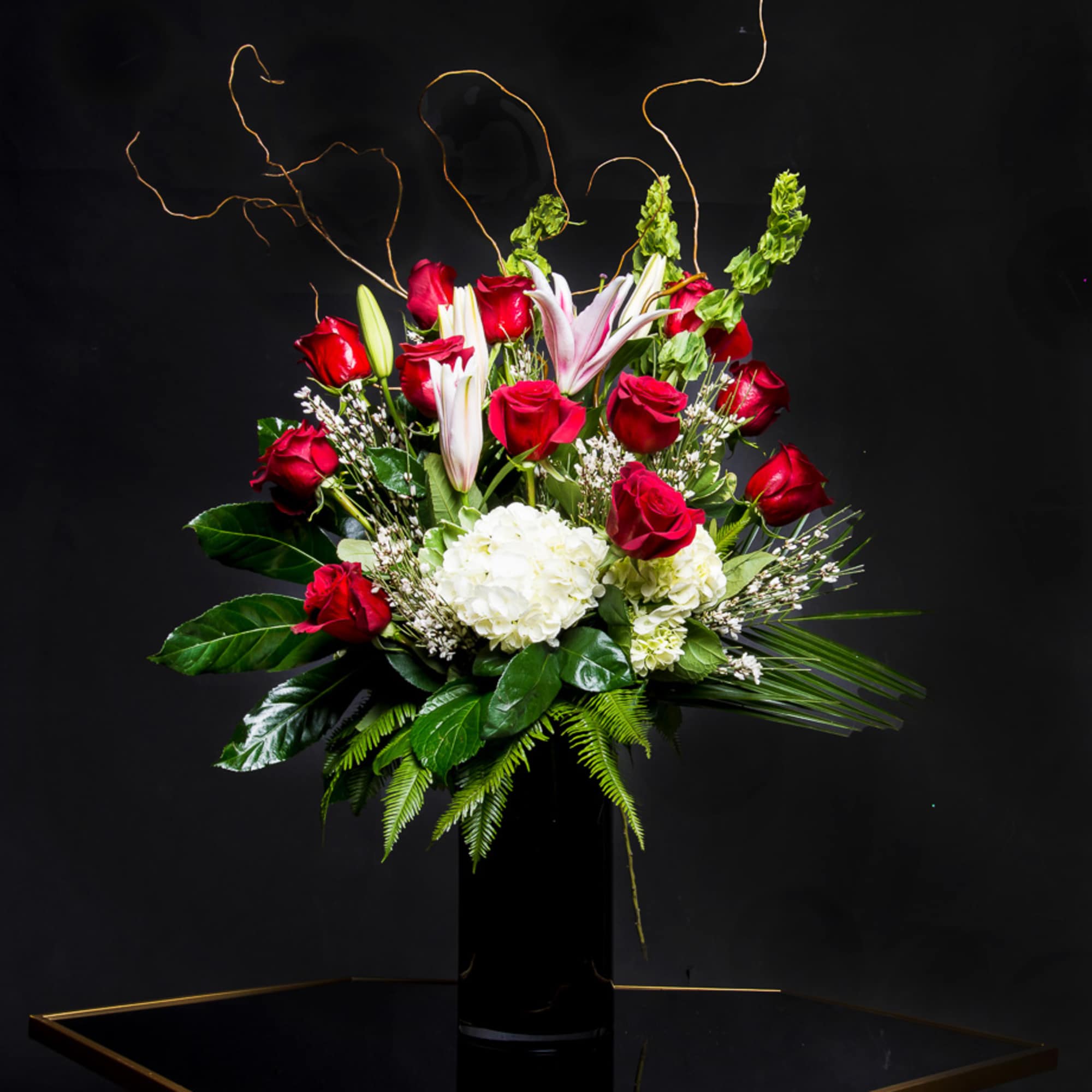 Red roses and white lilies arranged in a tall black vase