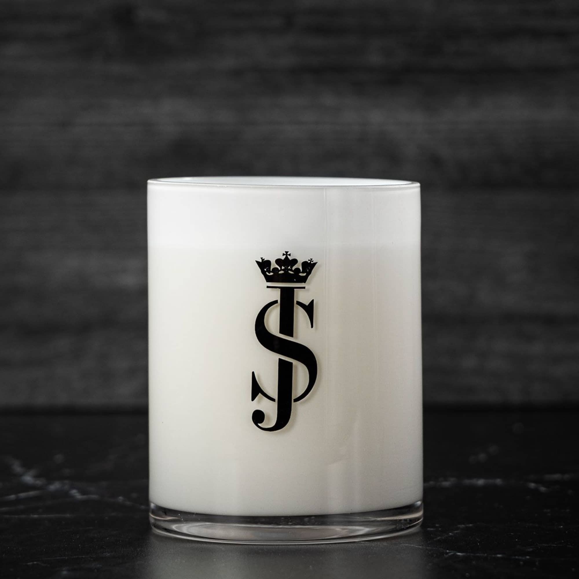 White glass candle with a black monogram logo