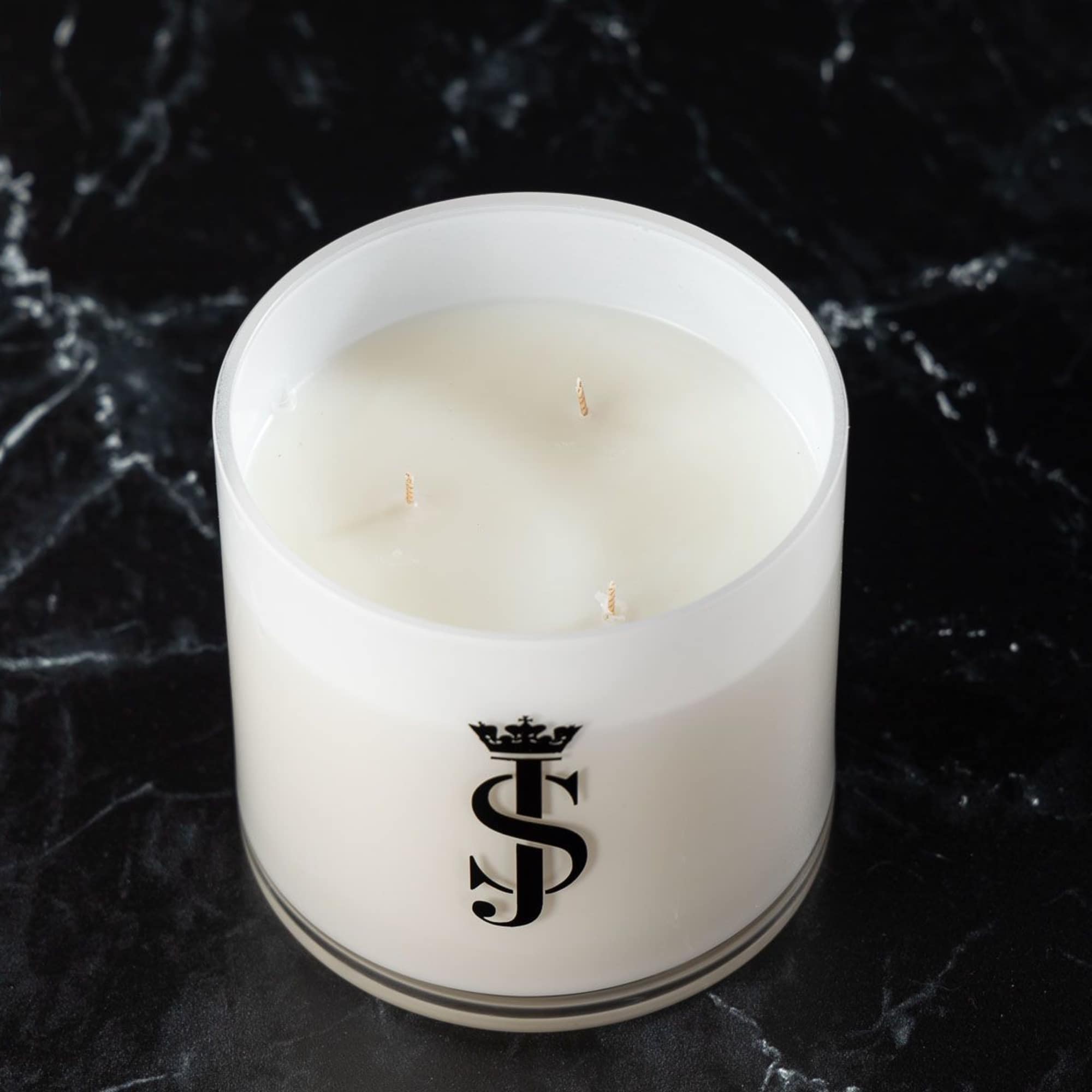 White three-wick candle in a glass jar with a black logo