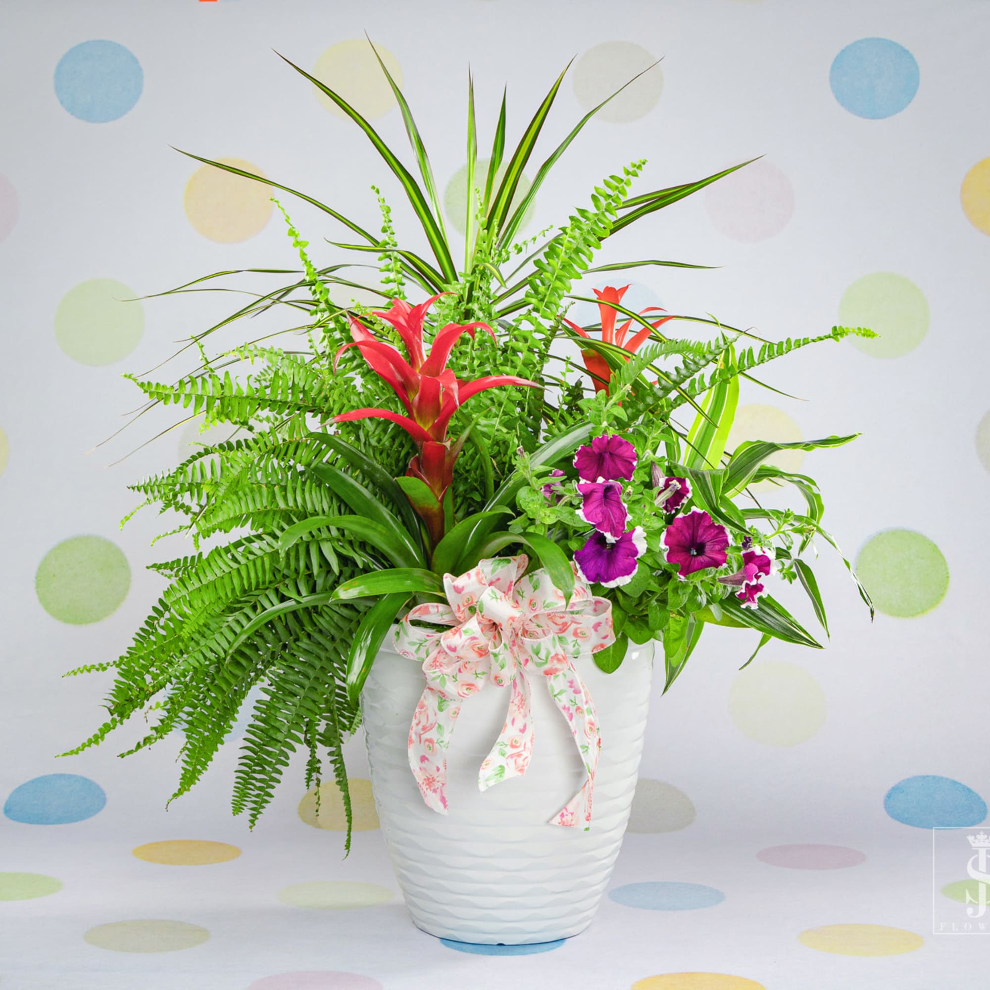 Tropical floral arrangement in a white vase with pink ribbon