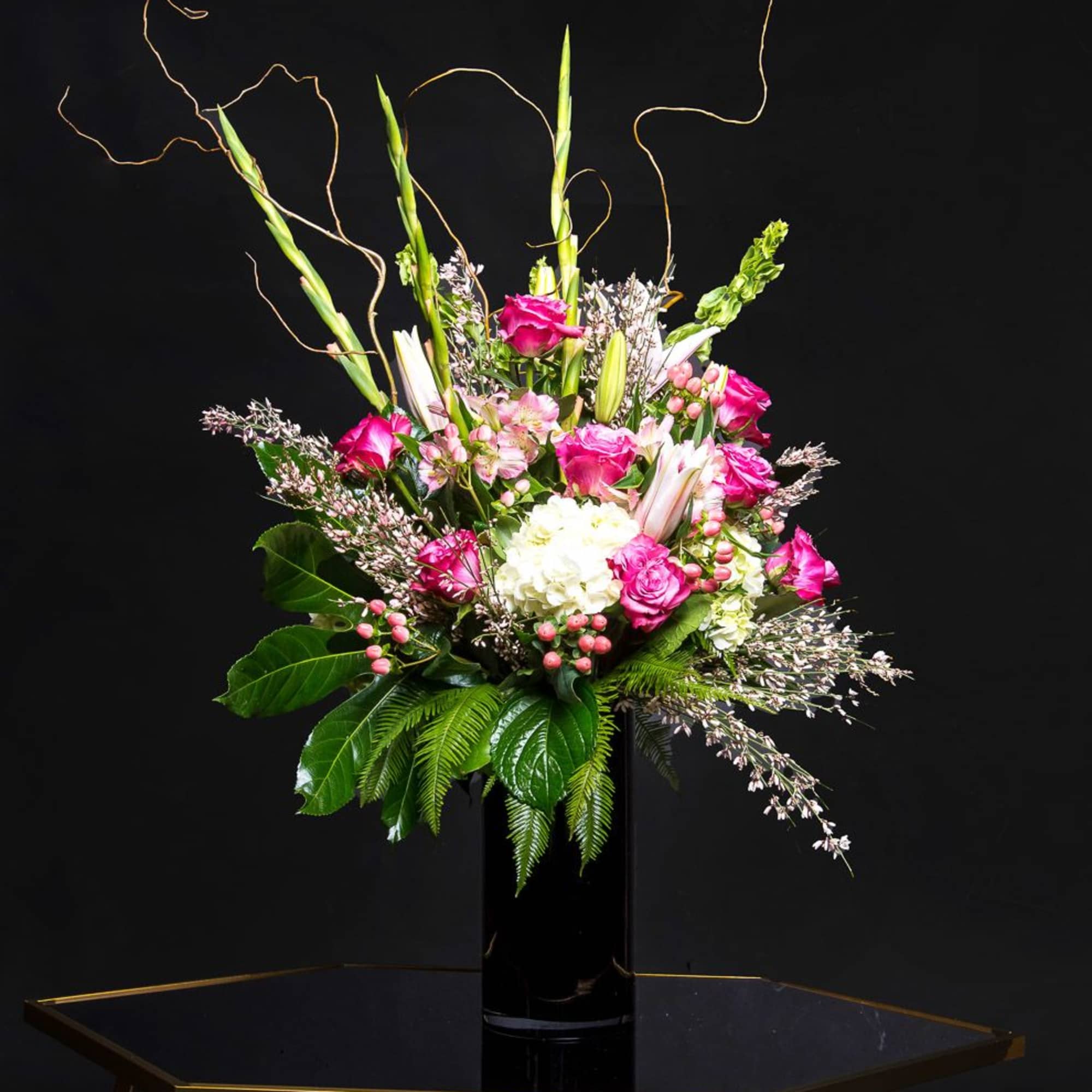 Tall pink and white floral arrangement in a black vase