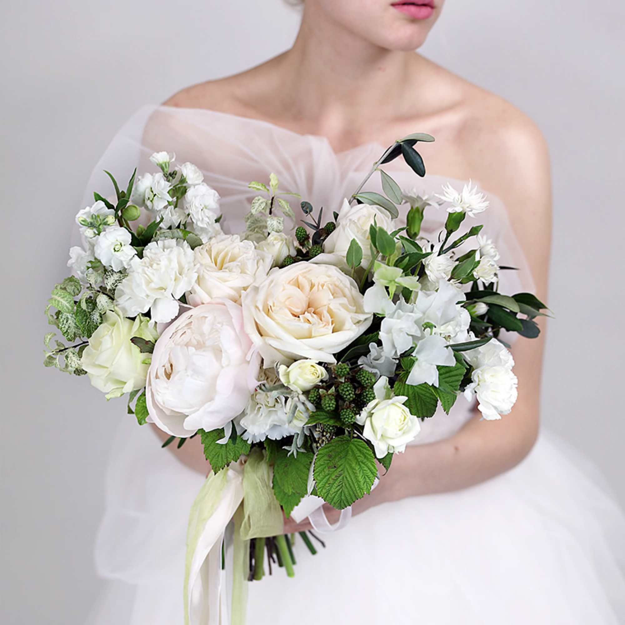 Bride holding a white and cream bouquet with green accents