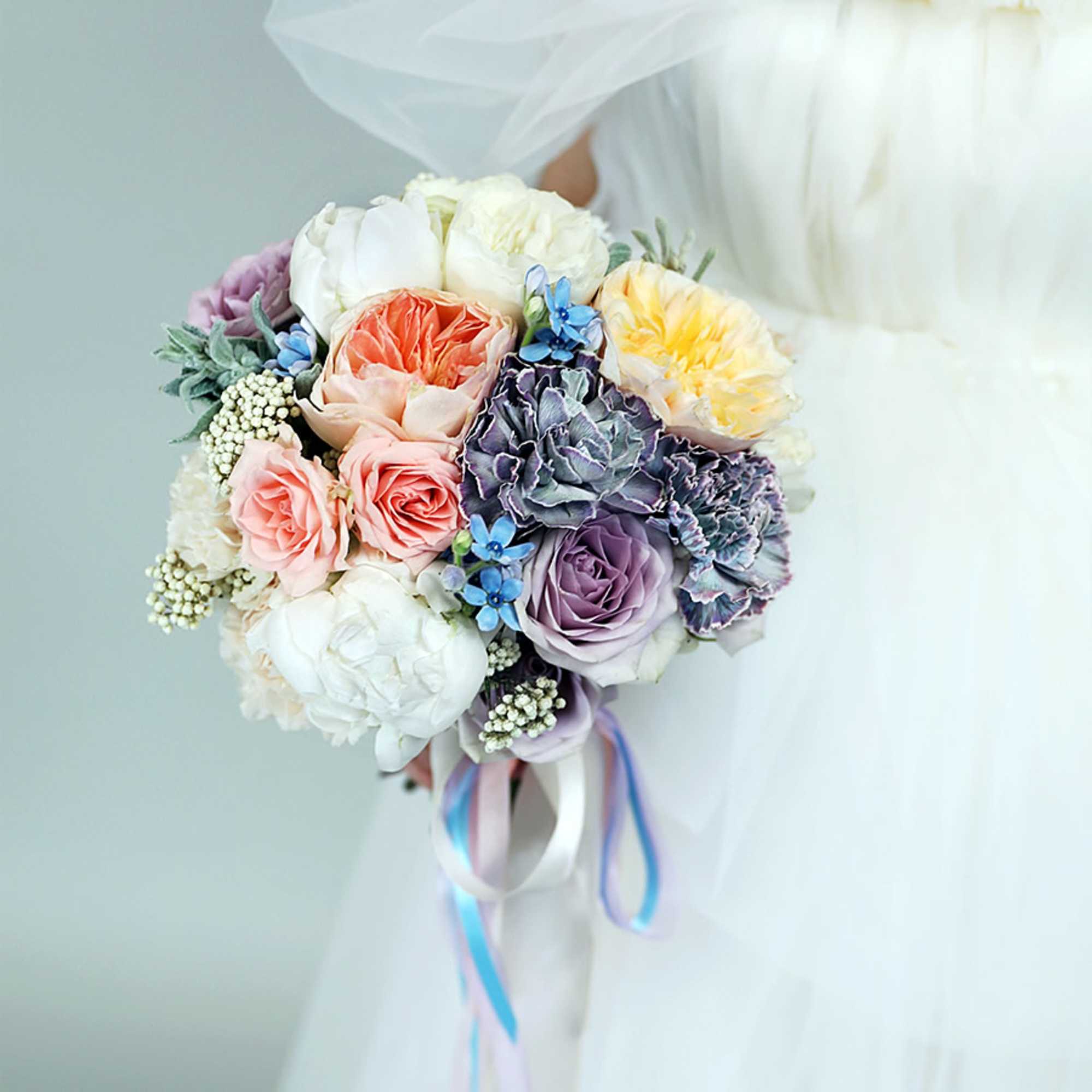 Pastel bridal bouquet with roses and carnations tied with ribbons