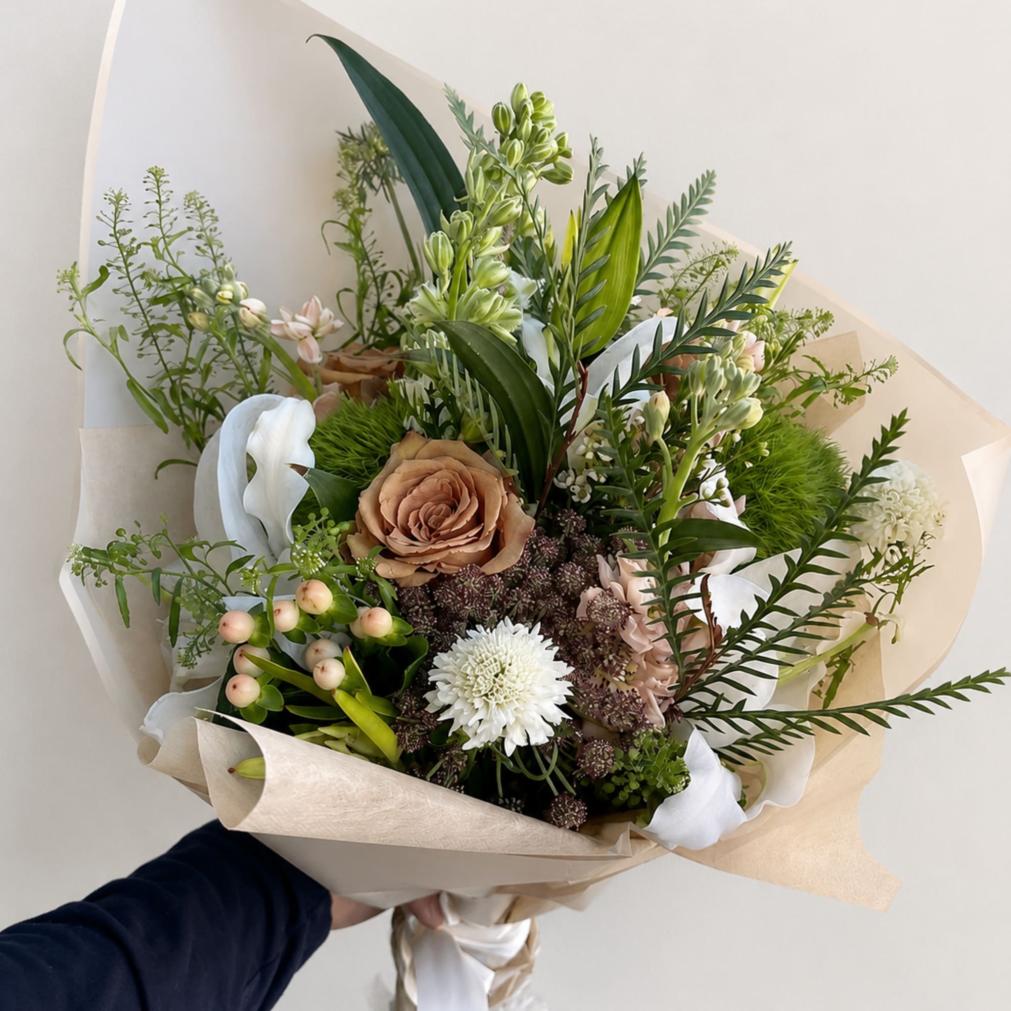 Hand-tied bouquet with tan, white, and pale pink flowers