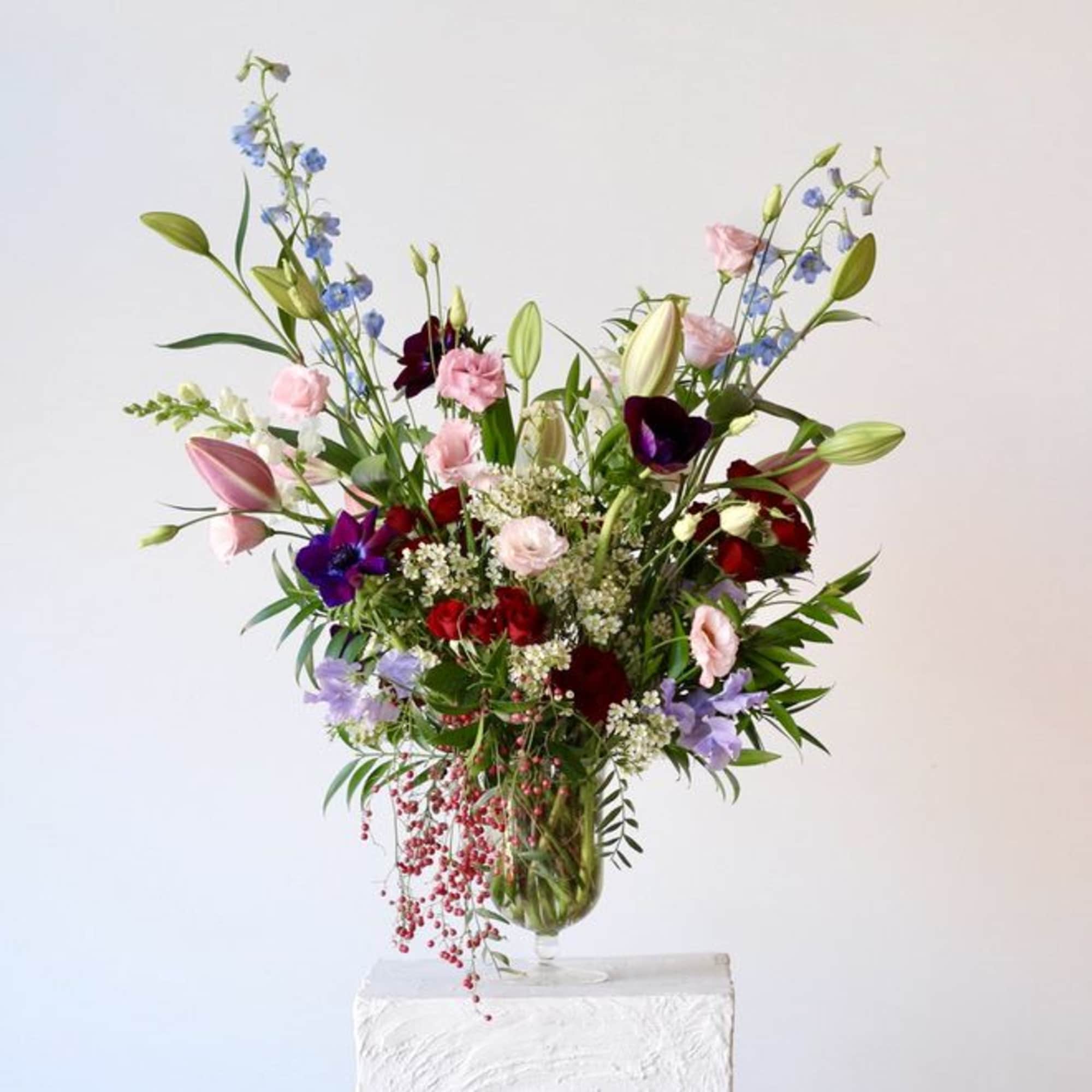 Tall mixed bouquet in a glass vase with pink, red, purple, and blue flowers