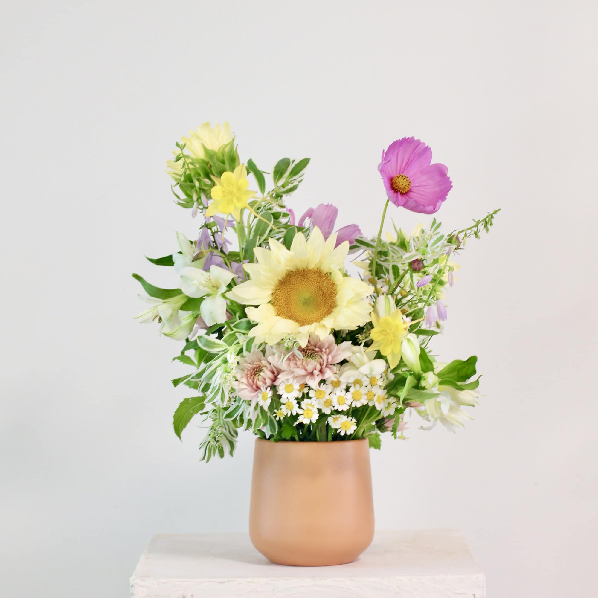 Mixed pastel flowers in a peach vase