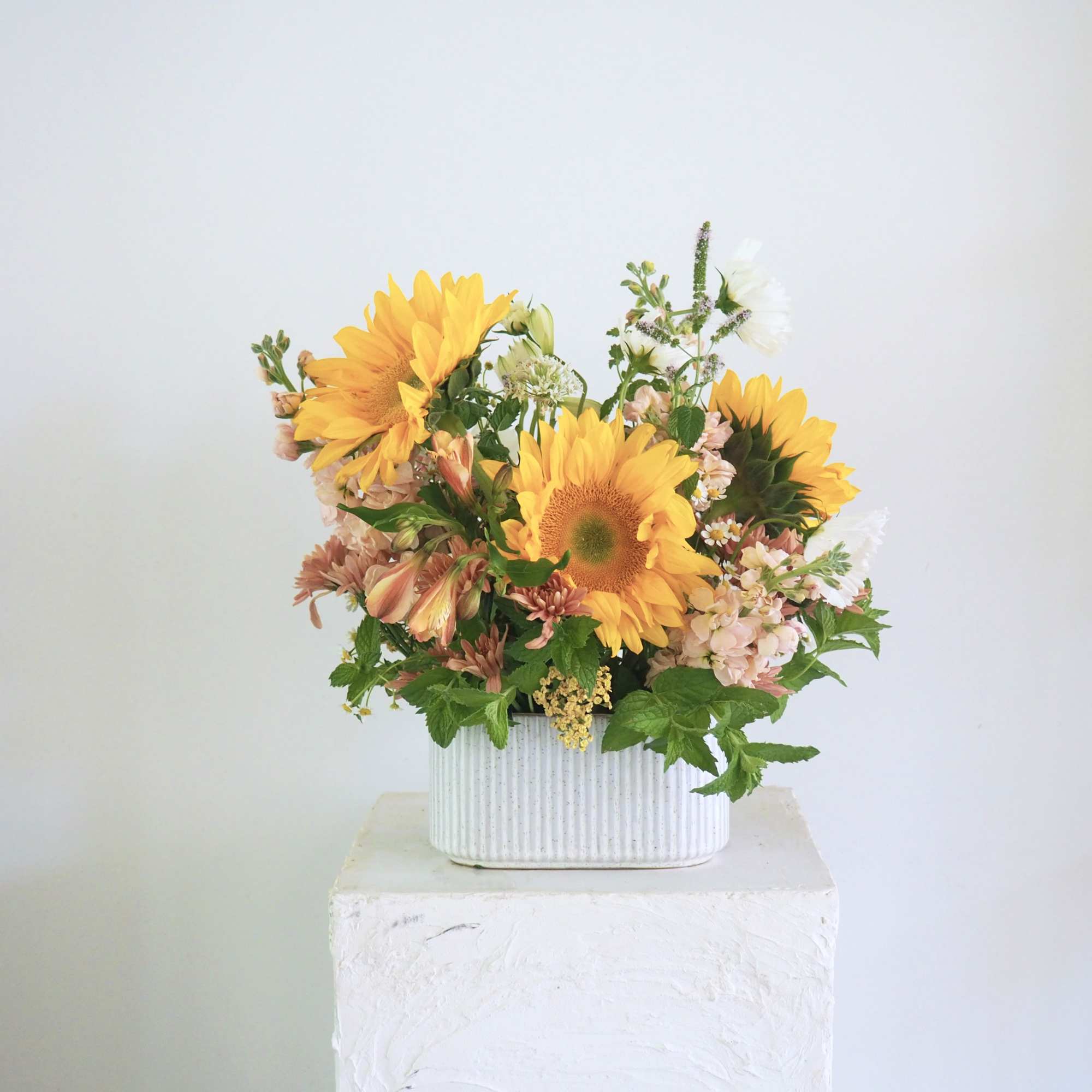 Sunflower arrangement in a white ribbed container
