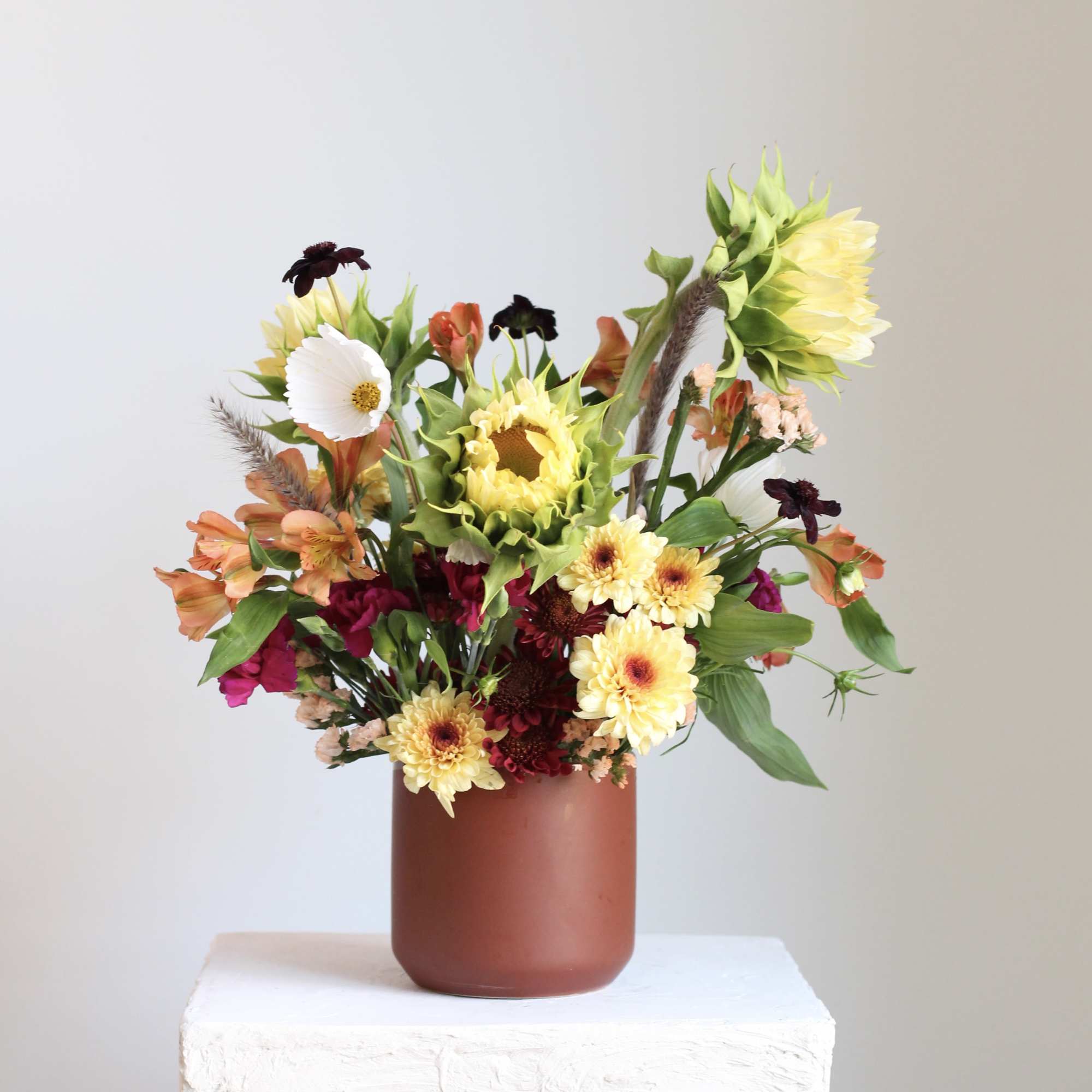 Mixed bouquet in a brown vase with sunflowers and orange blooms