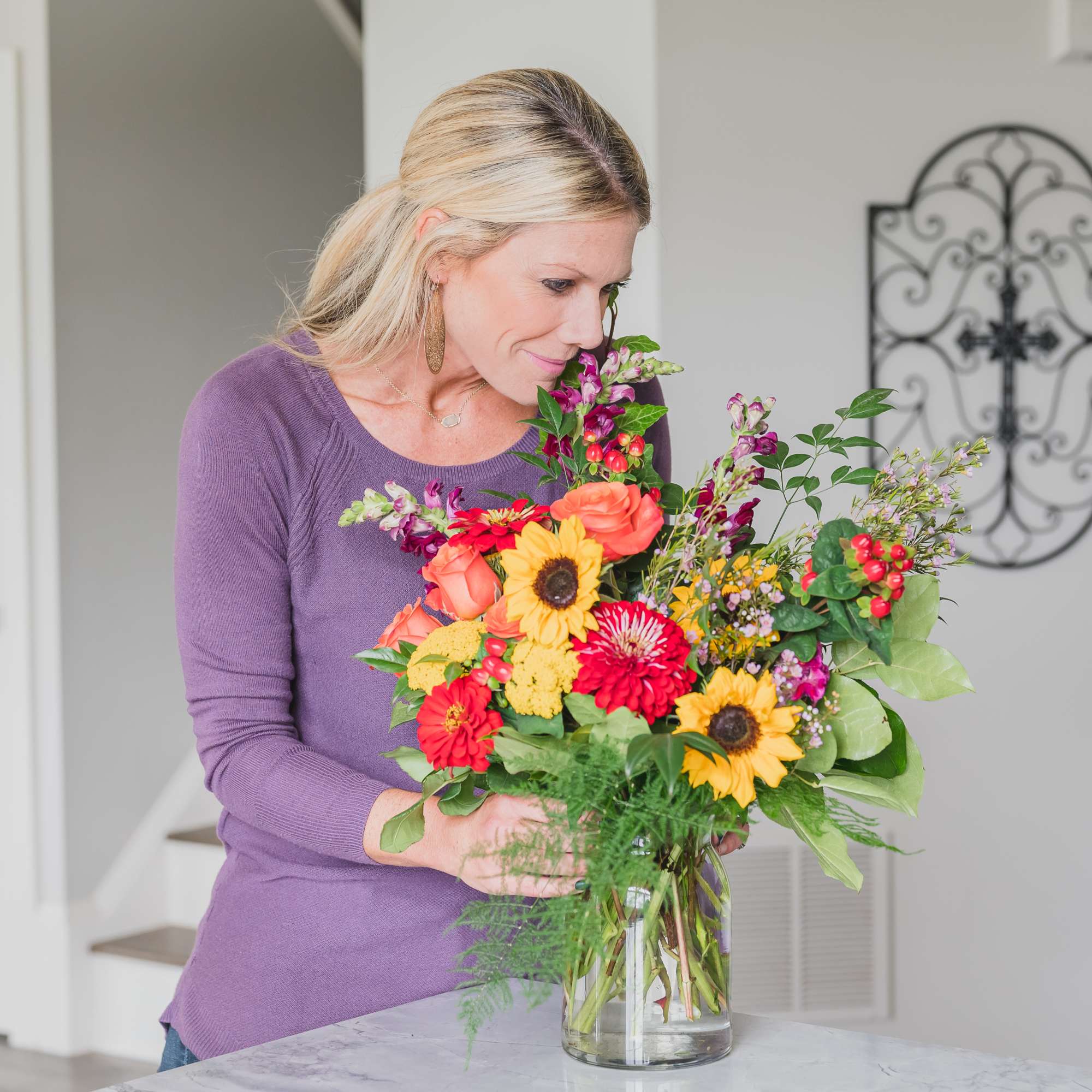 Woman arranging a colorful bouquet in a glass vase
