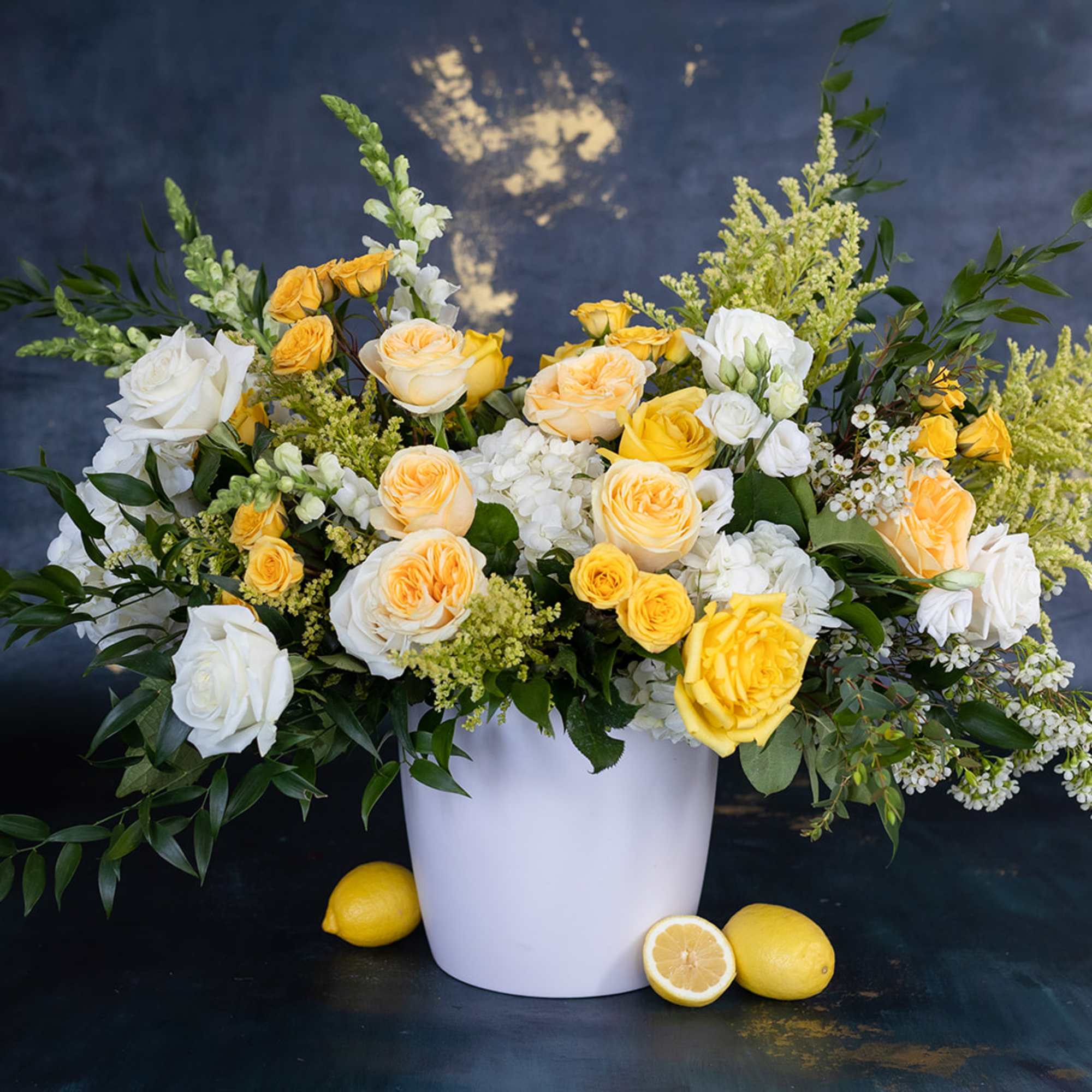 Yellow and white roses in a white vase with lemons