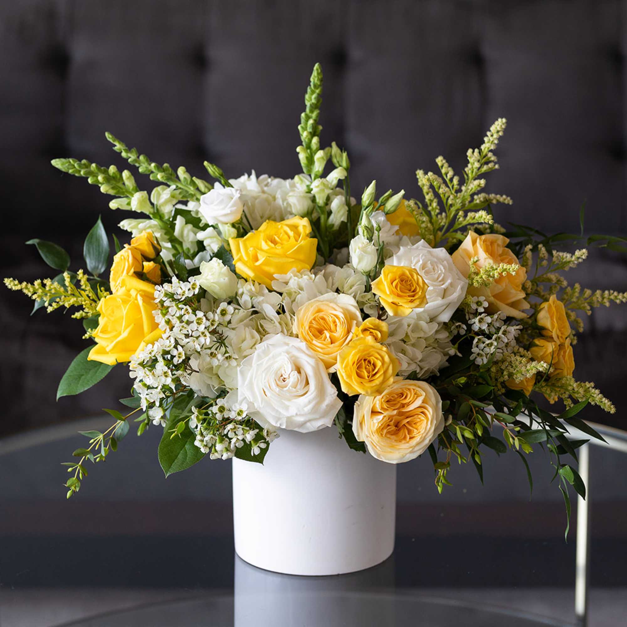 Yellow and white roses arranged in a white vase