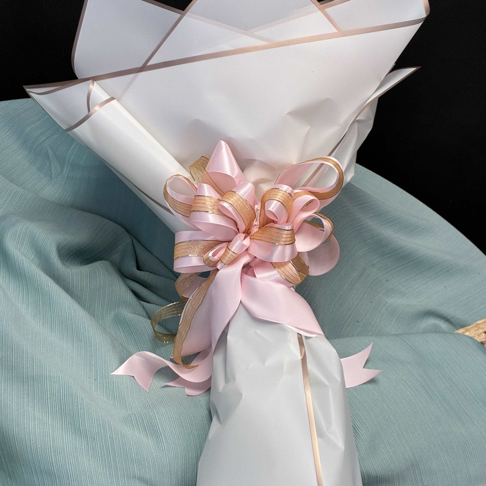 Wrapped gift bouquet with pink ribbon and gold accents