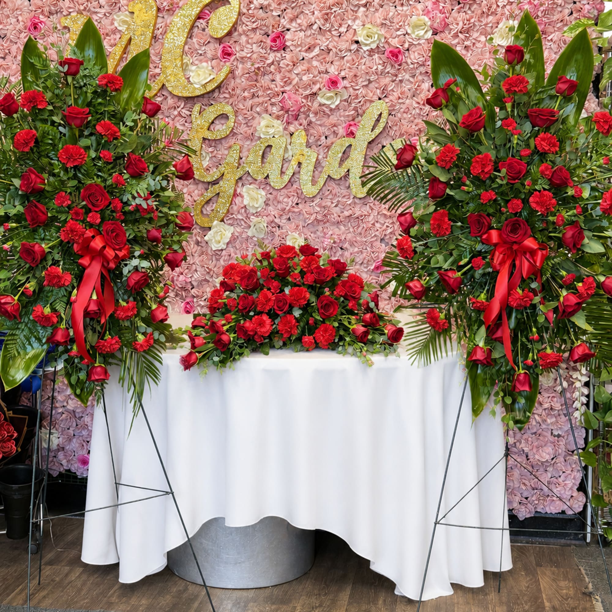 Large floral display with red roses and carnations against a pink flower wall