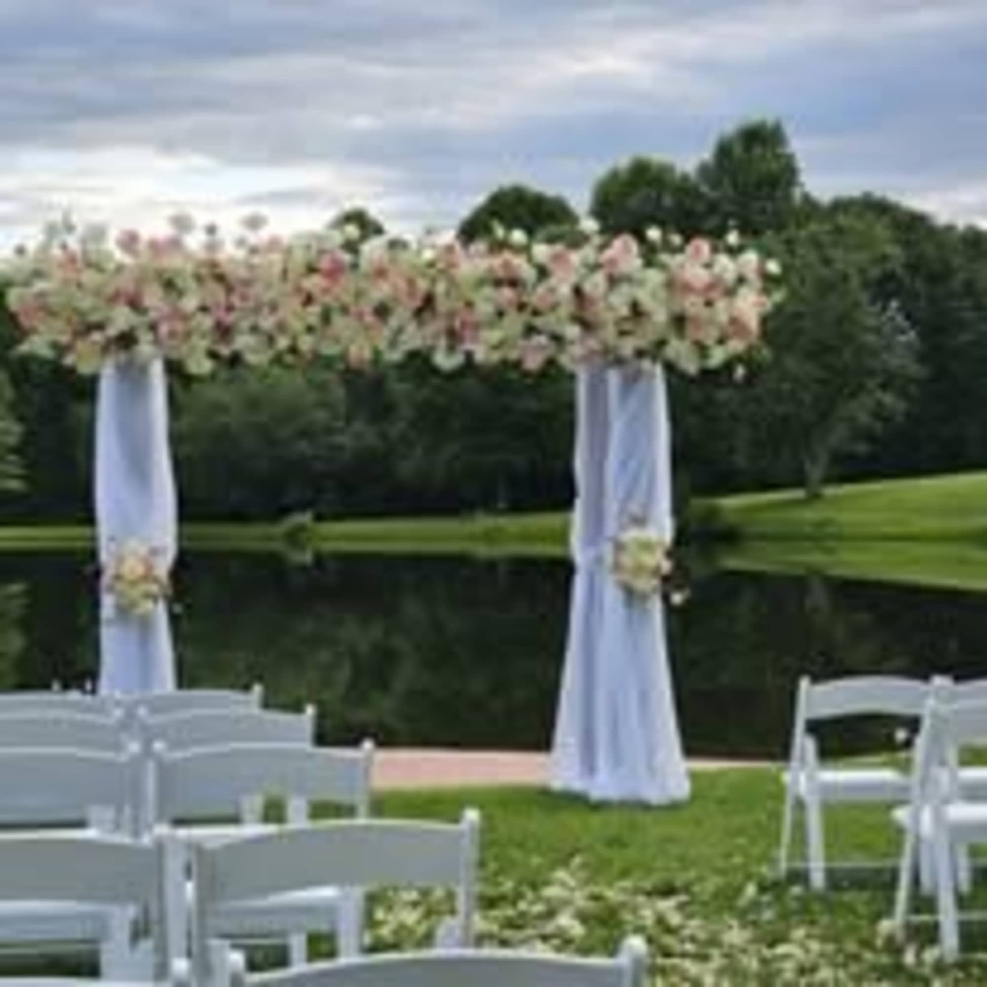 Wedding arch draped in white fabric with pale pink floral arrangements