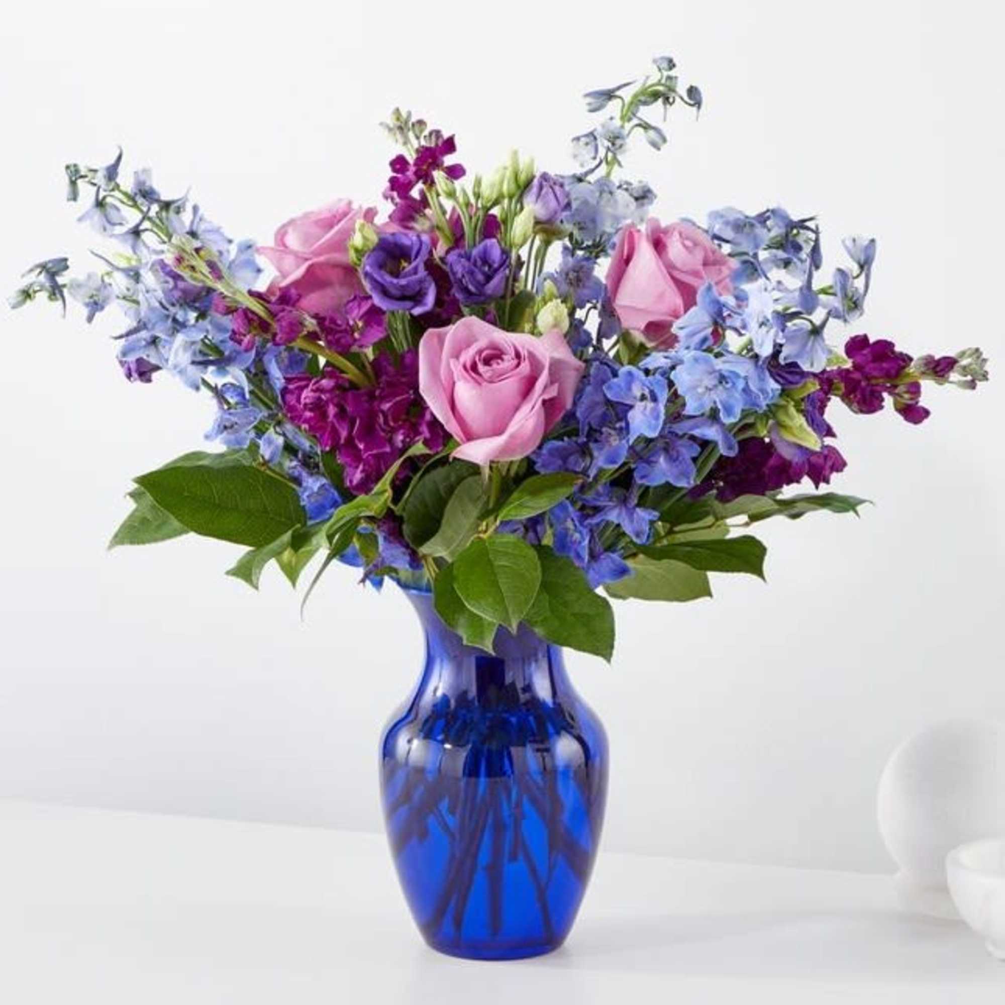 Pink roses and purple-blue flowers in a cobalt glass vase