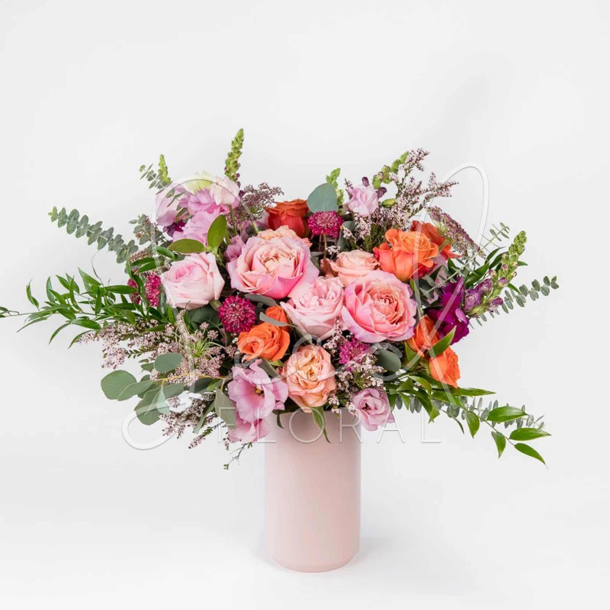 Pink and orange rose bouquet in a tall blush vase