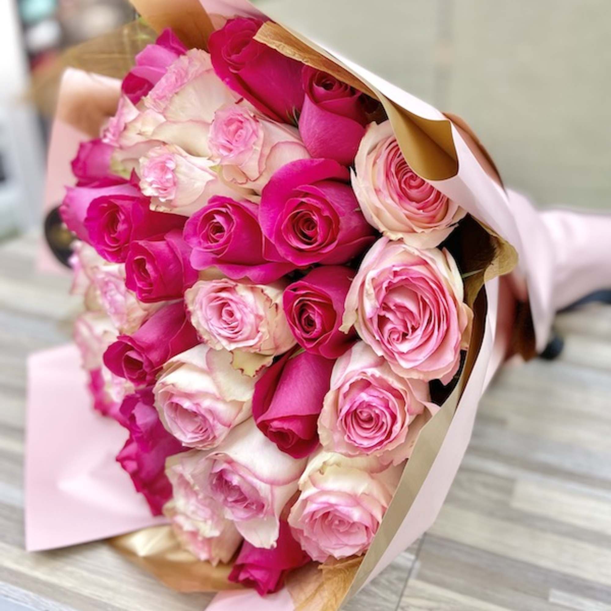 Bouquet of hot pink and light pink roses wrapped in pink and kraft paper