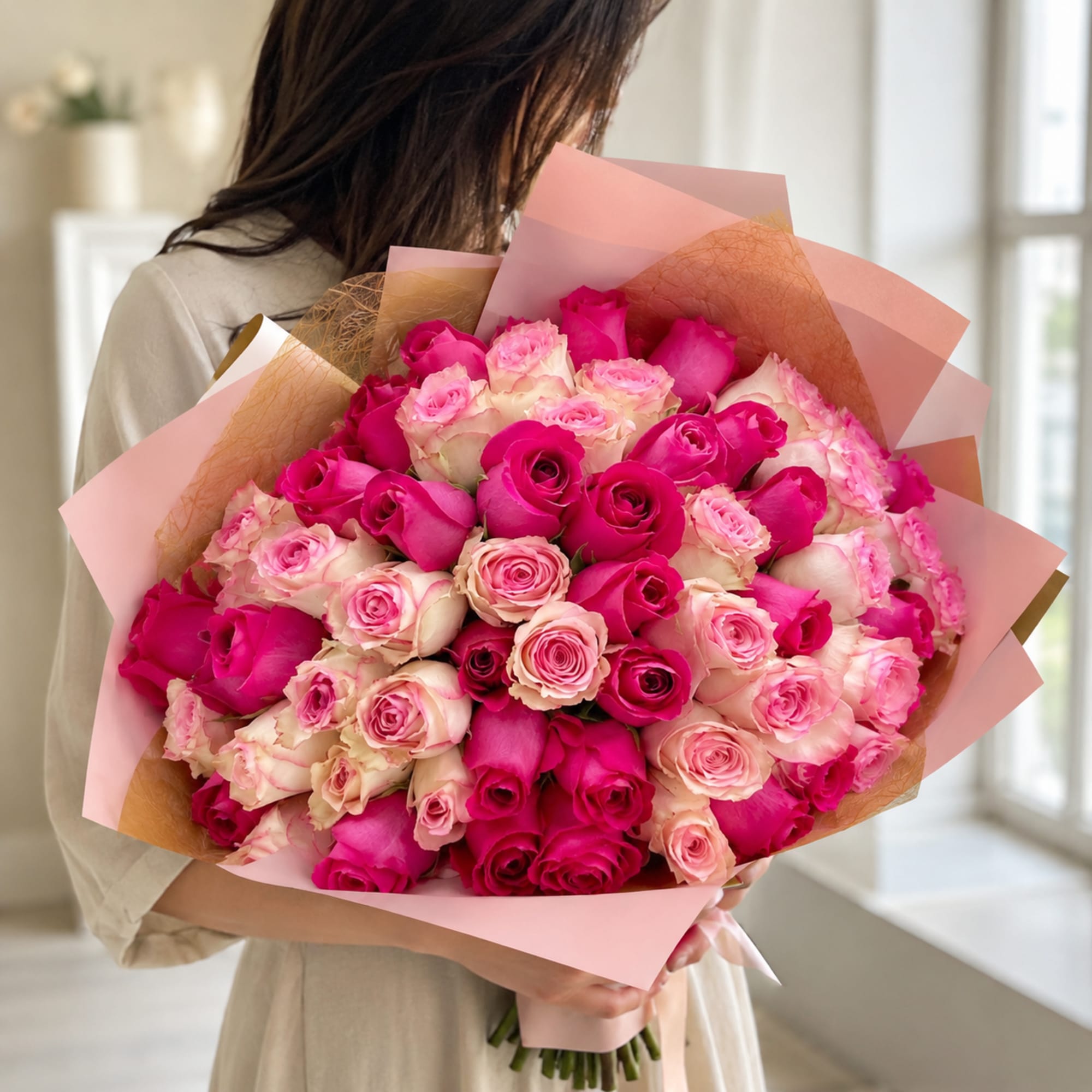 Large bouquet of pink and cream roses wrapped in pink paper