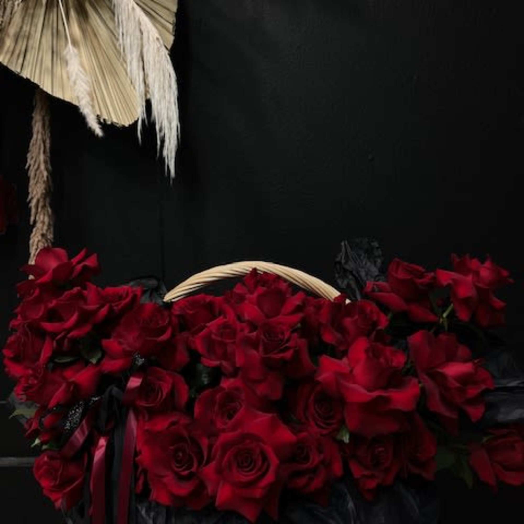 A huge brown basket with beautiful large, inverted roses with long ribbons