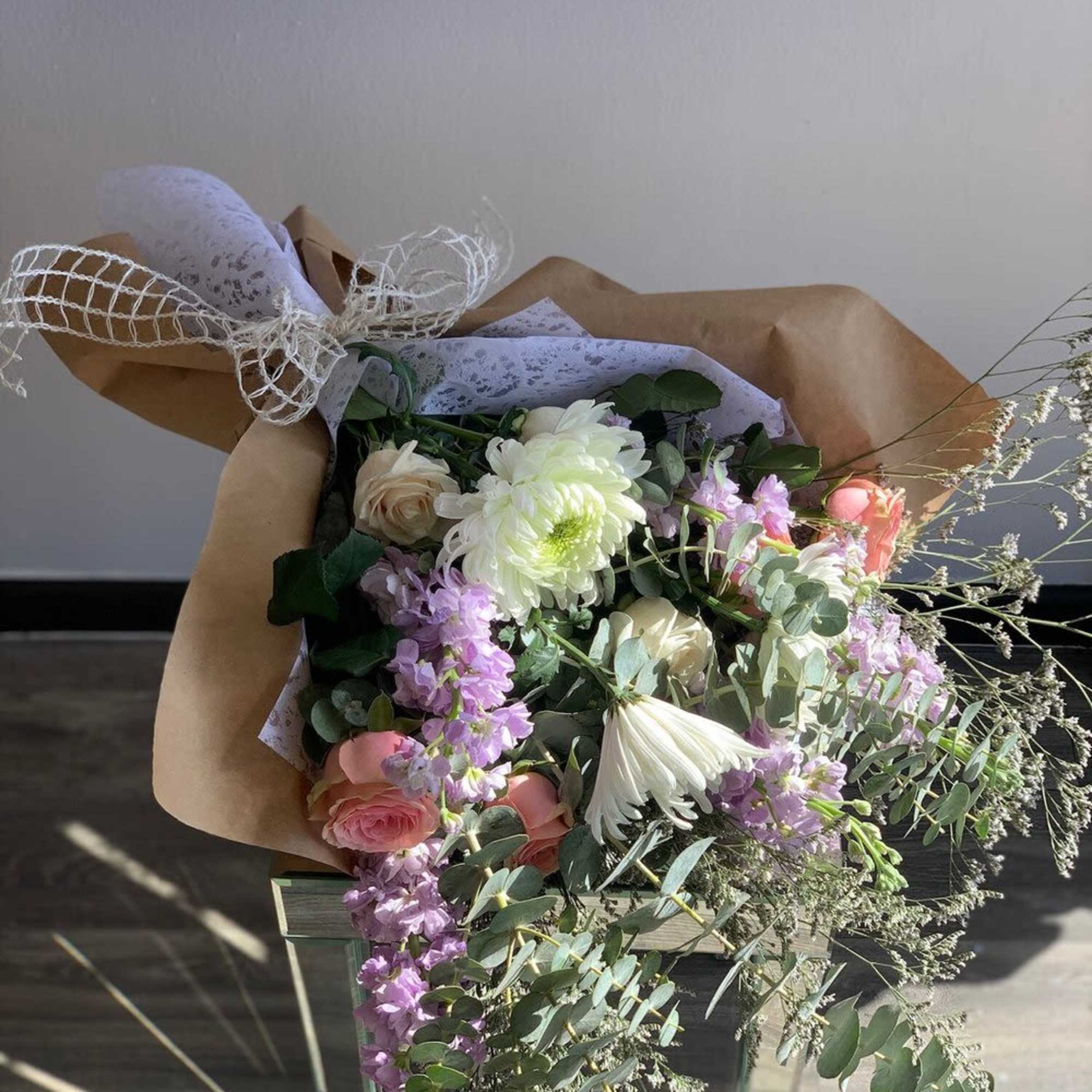 Bouquet of pink, white, and lavender flowers wrapped in brown paper