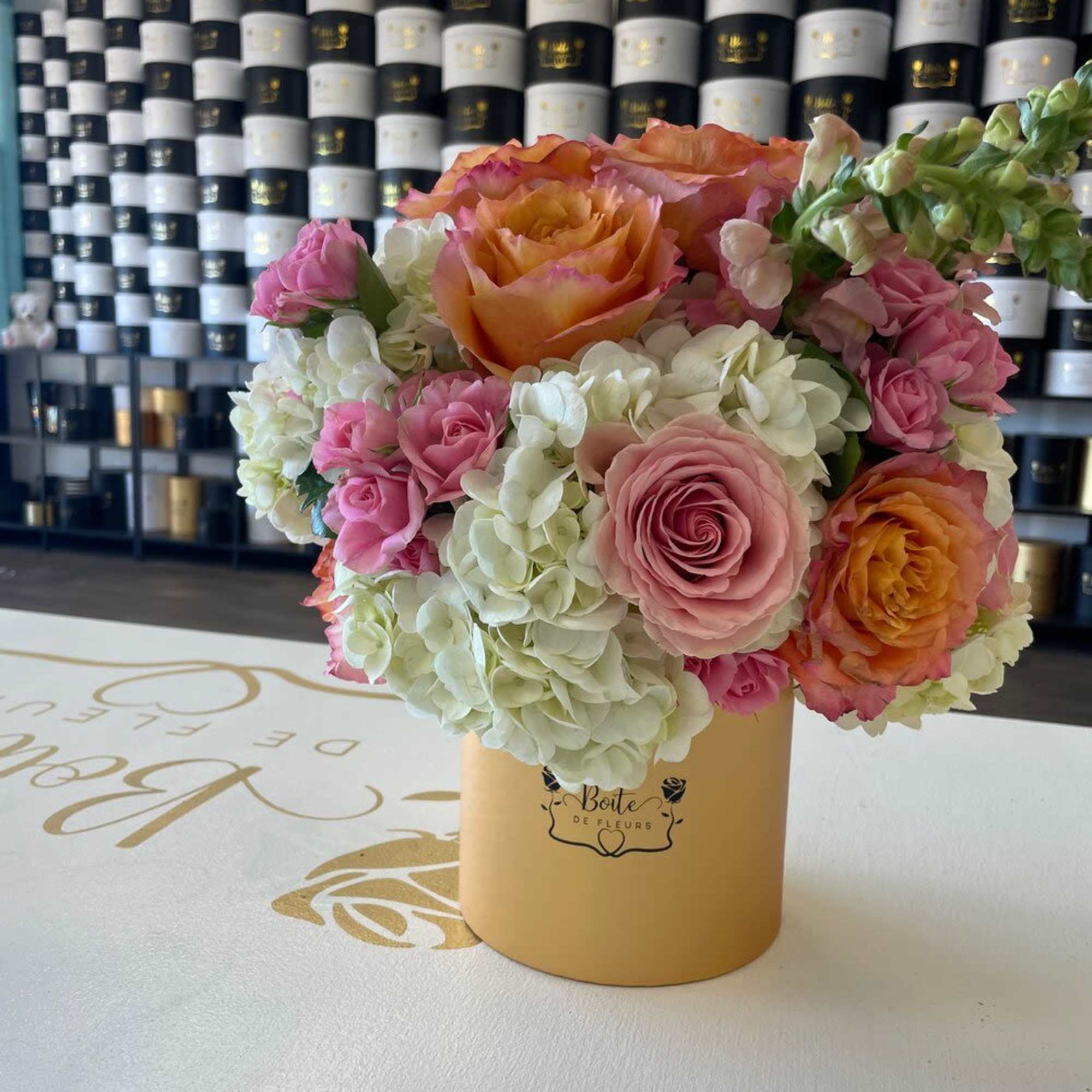 Pink and orange roses with white hydrangeas in a gold box