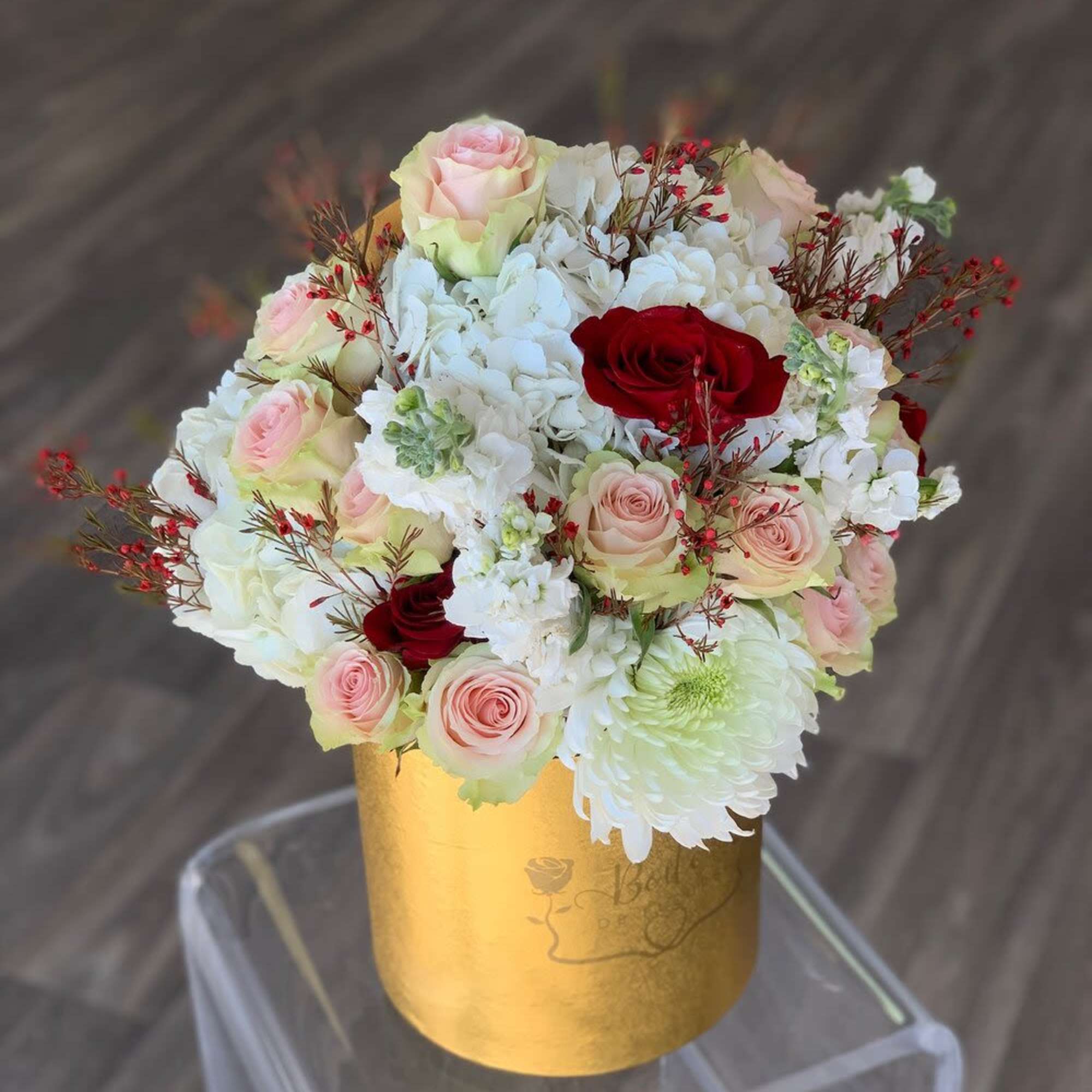 Bouquet of pink and red roses with white blooms in a gold box