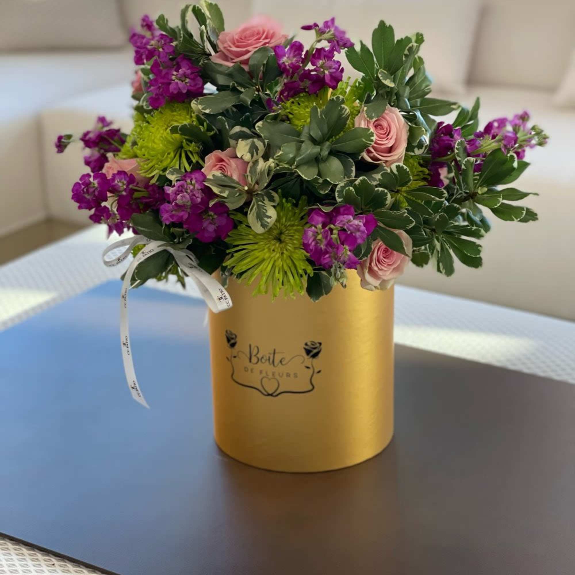 Pink roses and purple flowers arranged in a gold box