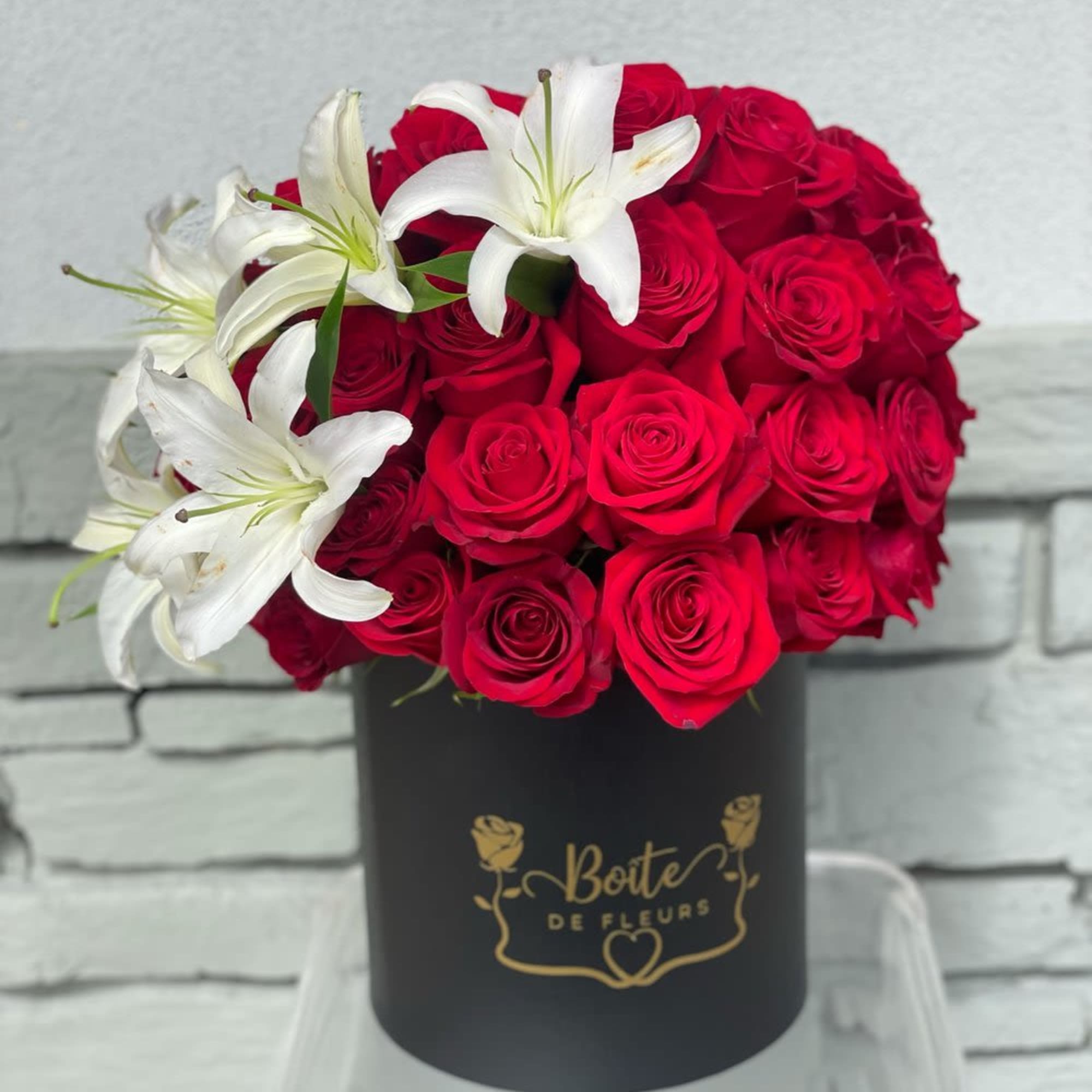 Red roses with white lilies in a black hat box