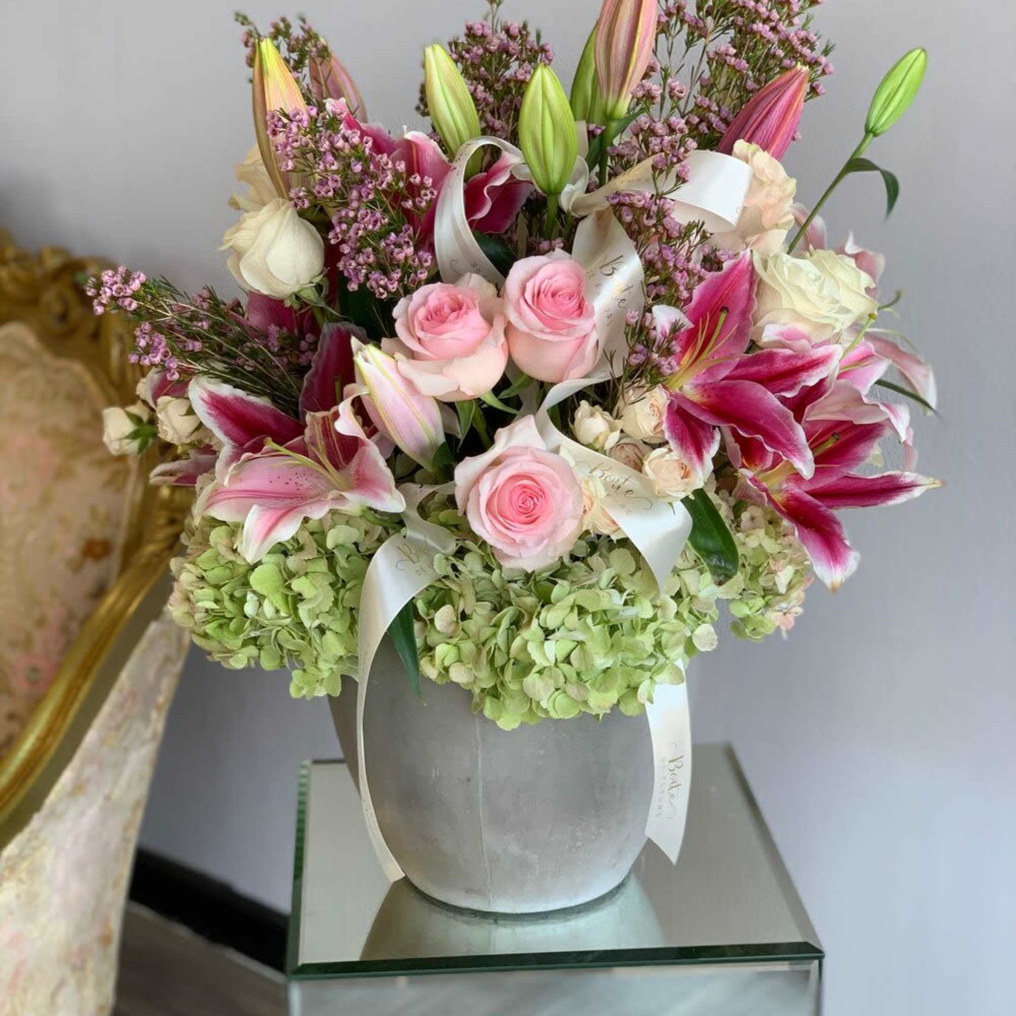 Pink lilies and roses arranged in a gray vase