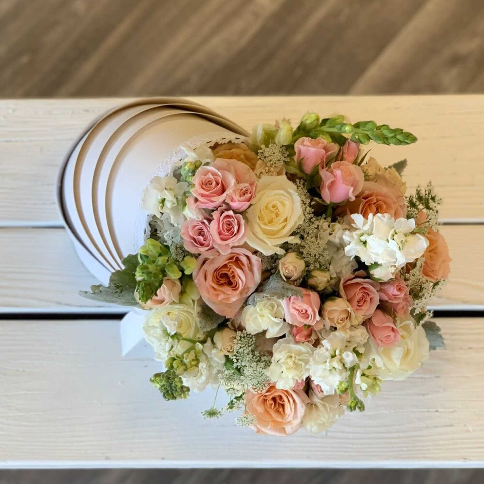 Round bouquet of pink, peach, and white roses on a white chair