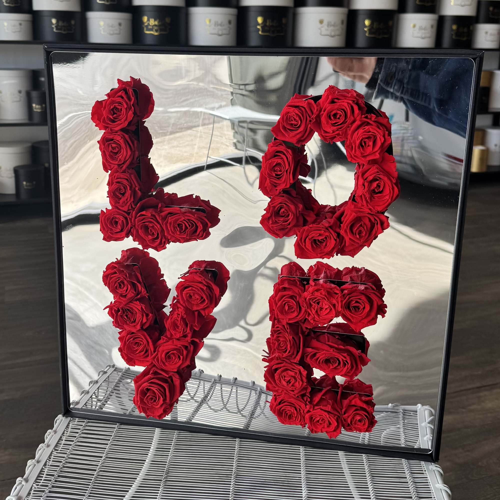 Red roses arranged as the numbers 1, 0, 1, and 5 in a mirrored frame