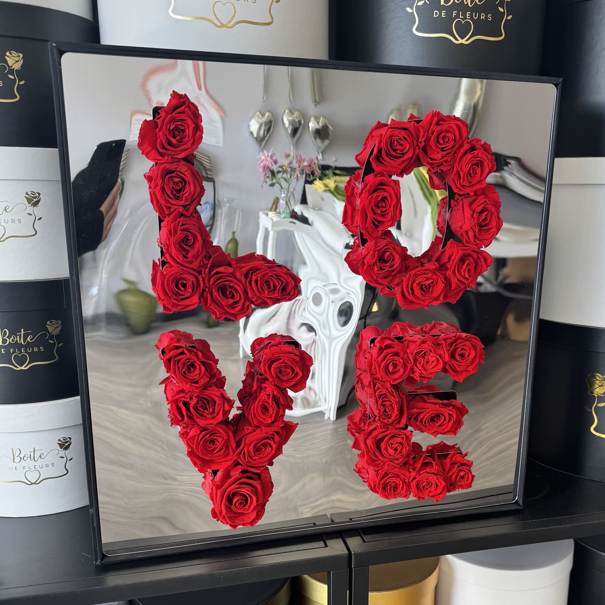 Red roses arranged to spell "LOVE" in a black frame box