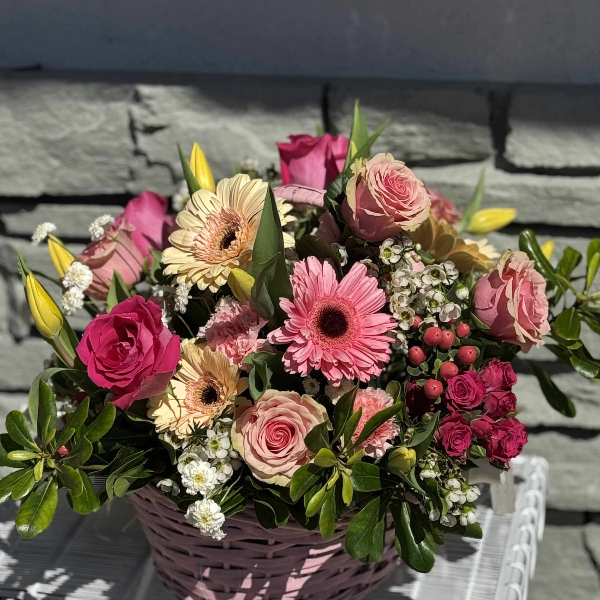 Pink and cream mixed flower arrangement in a pink basket