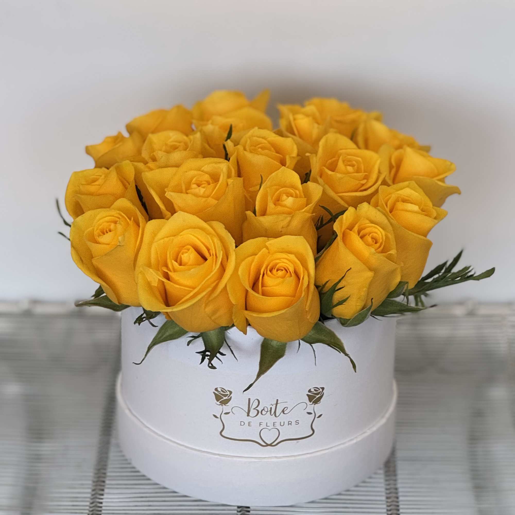 Yellow roses arranged in a white round box