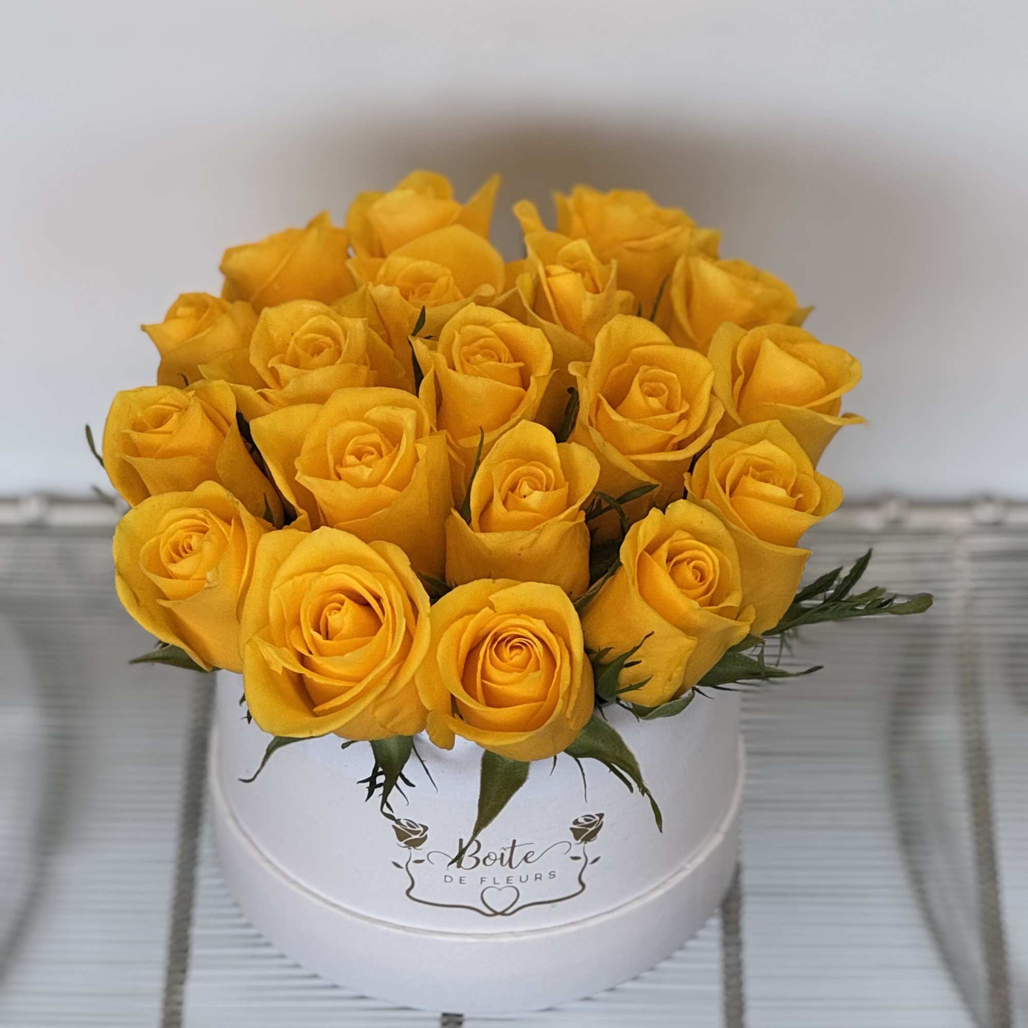 Yellow roses arranged in a white round box