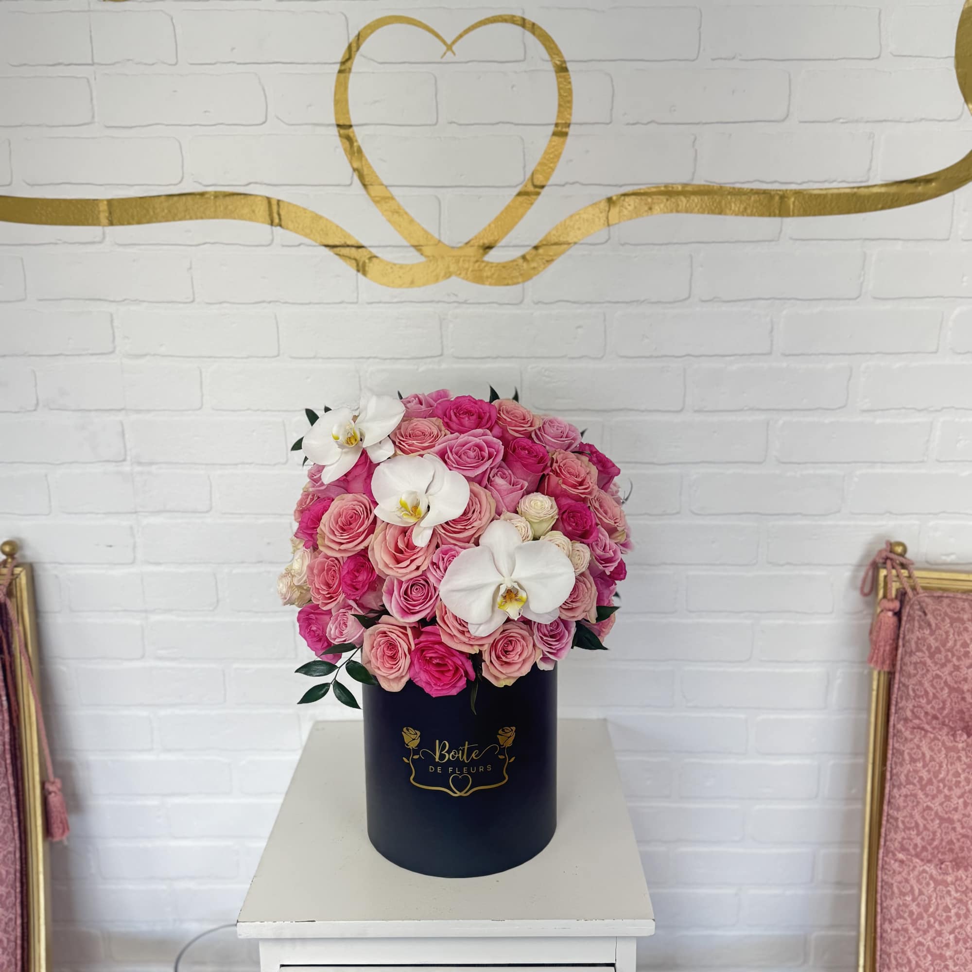 Pink rose arrangement in a navy cylindrical box with white orchids