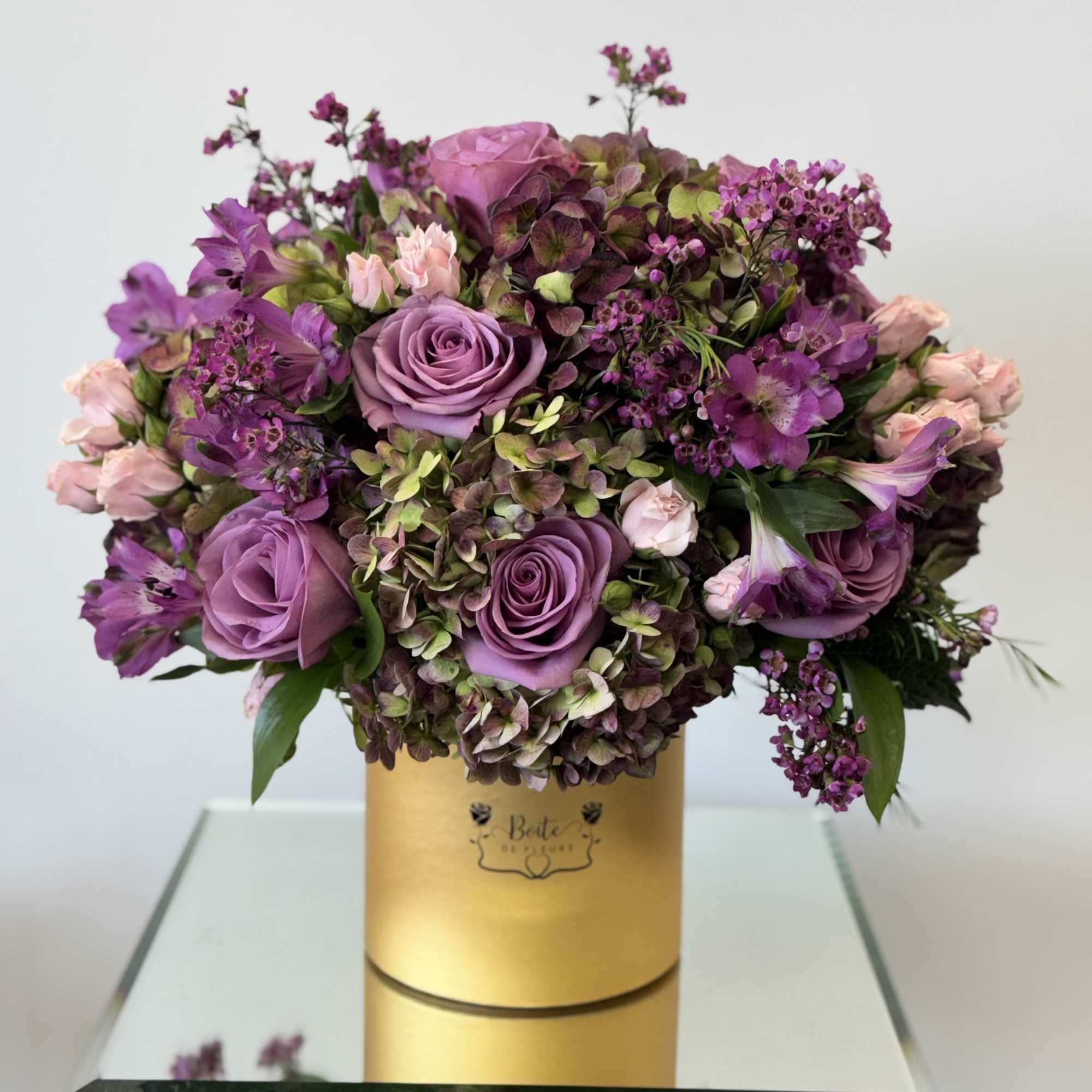 Purple and pink rose bouquet in a gold hatbox