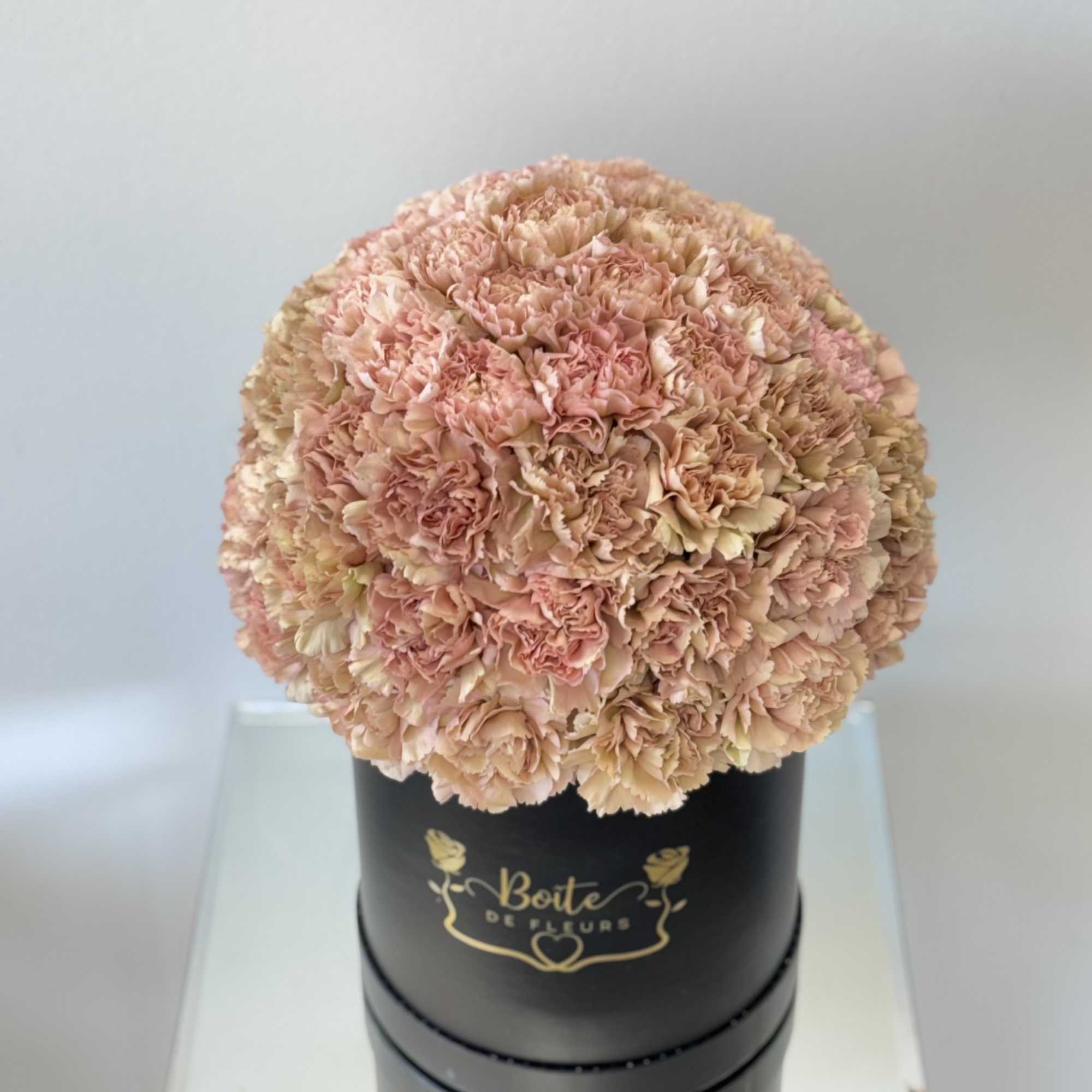 Round bouquet of pale pink carnations in a black hat box