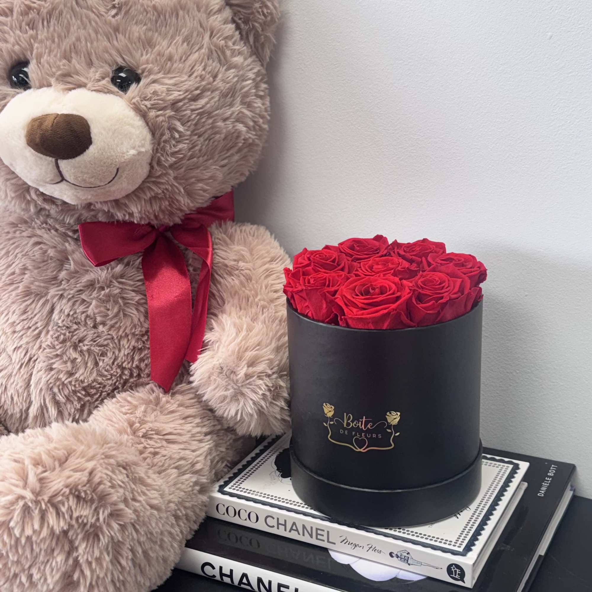 Teddy bear beside a black box of red roses