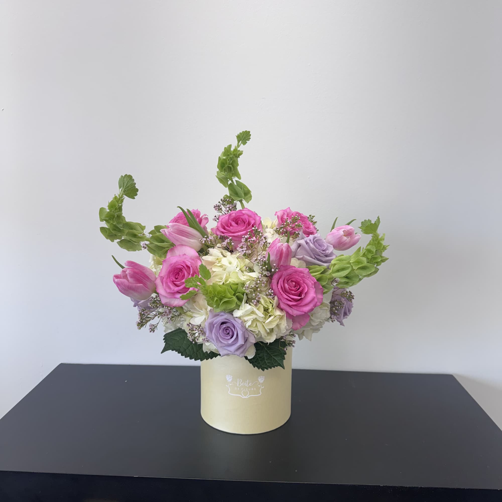 Pink and lavender roses with tulips in a cream box