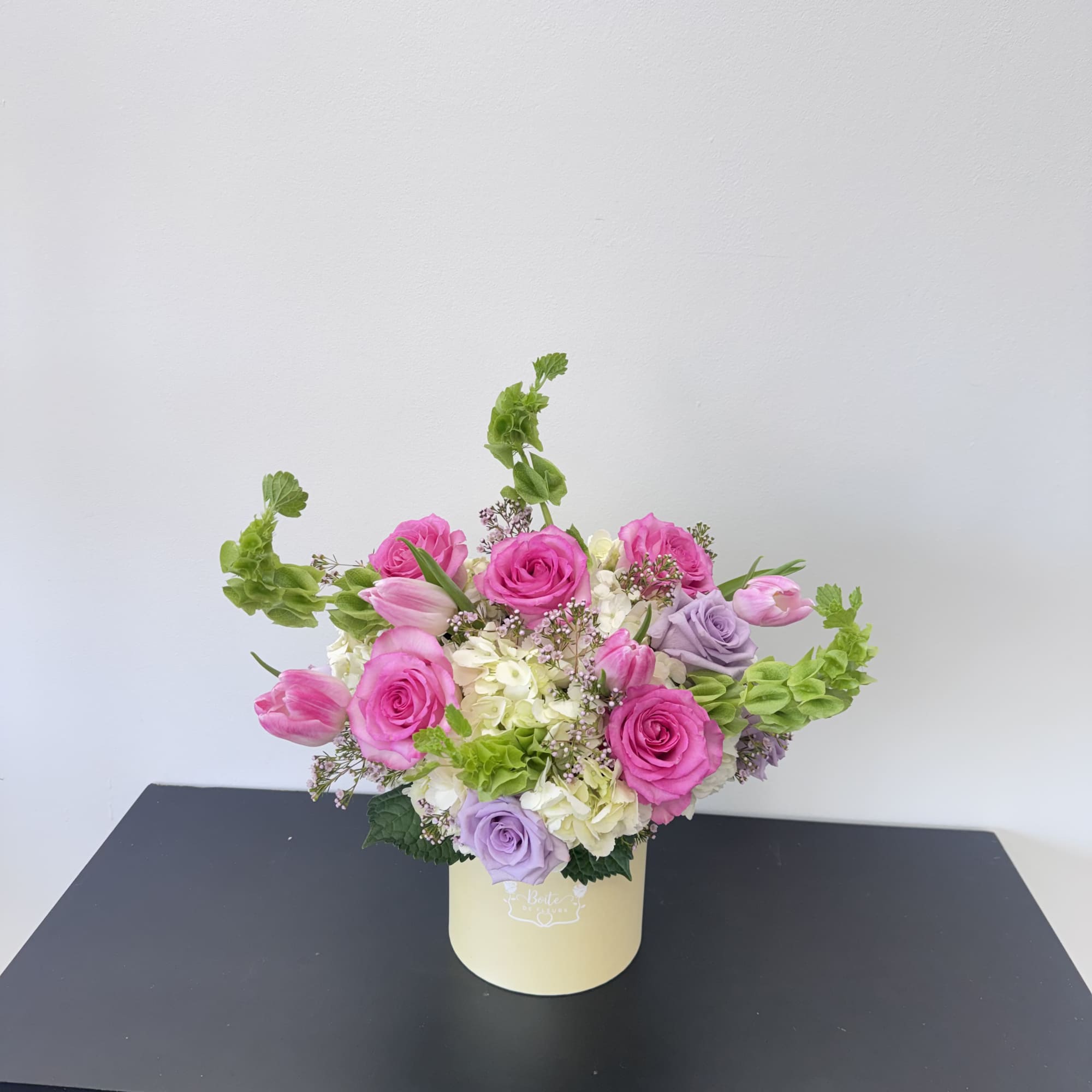 Pink and lavender roses arranged in a pale yellow box