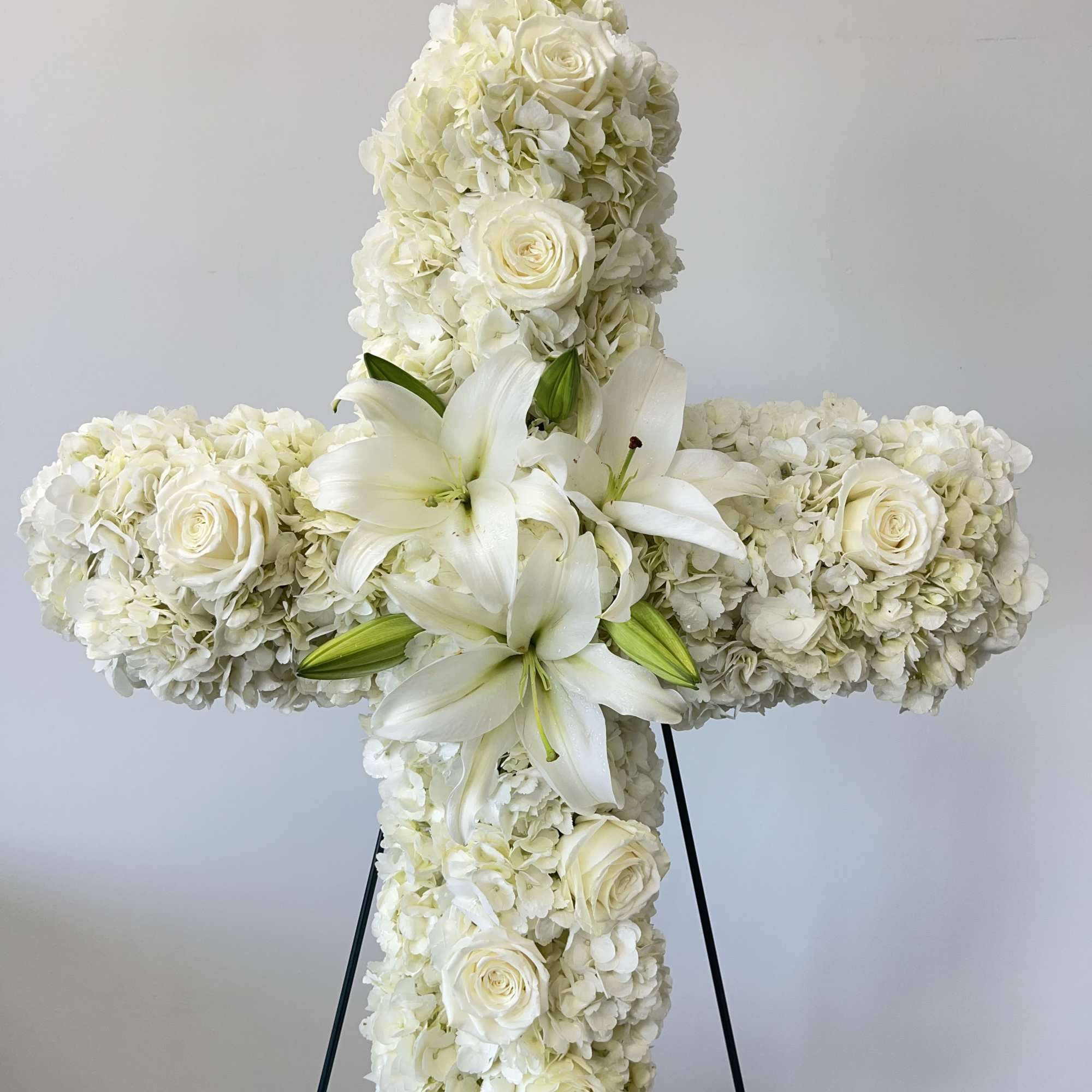 An all white tribute, this white cross funeral spray is pure and