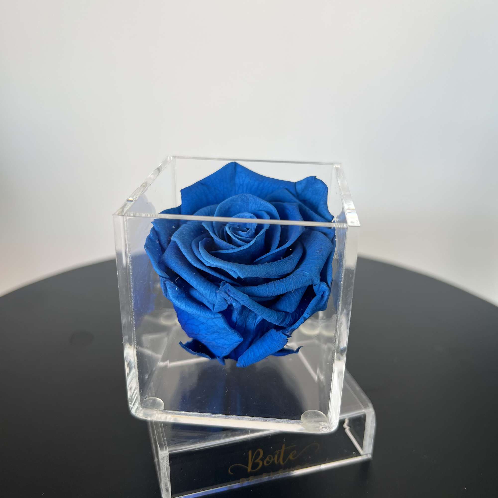 A single forever rose sits in a custom acrylic box. This petit