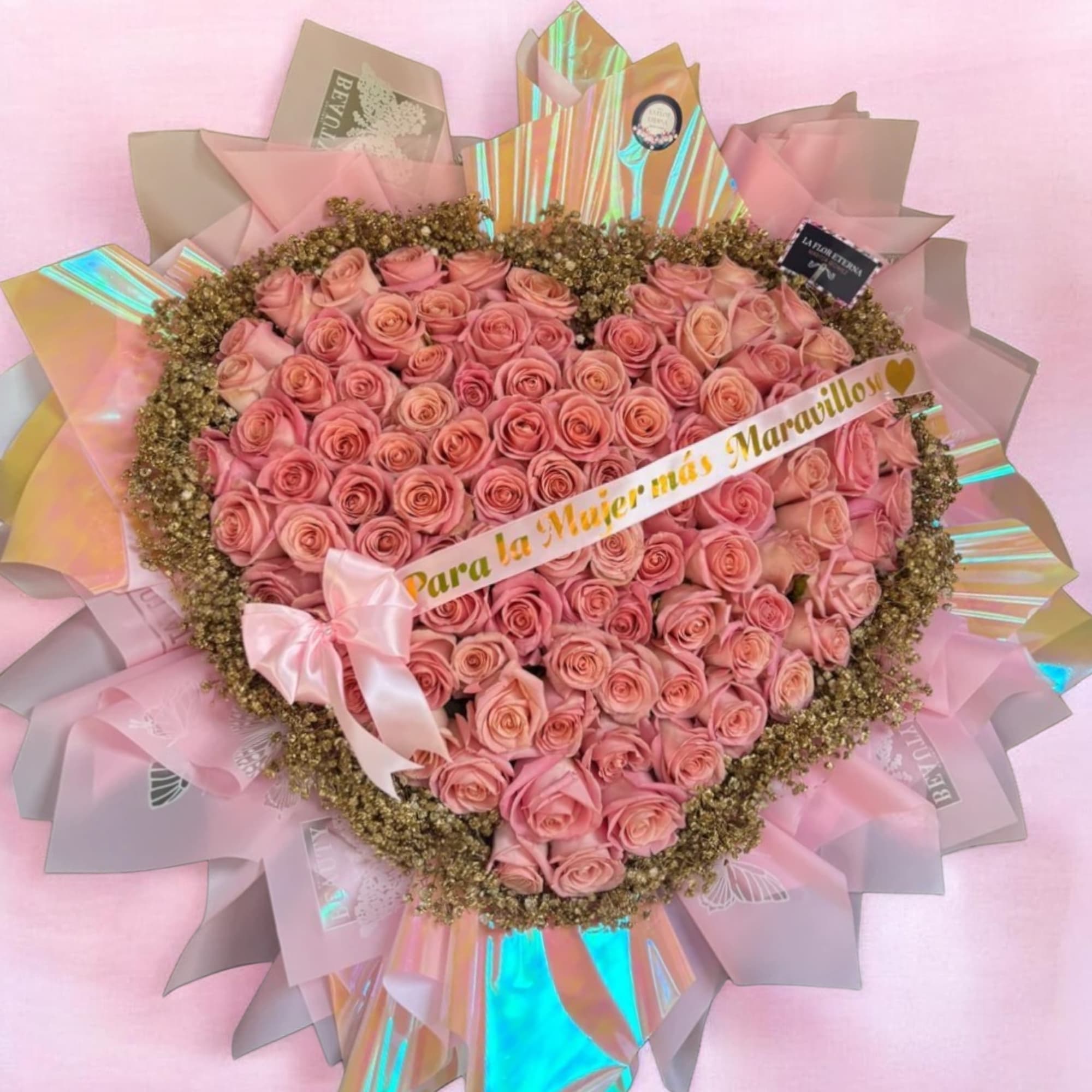 A lush heart-shaped arrangement of soft pink and peach roses forms a