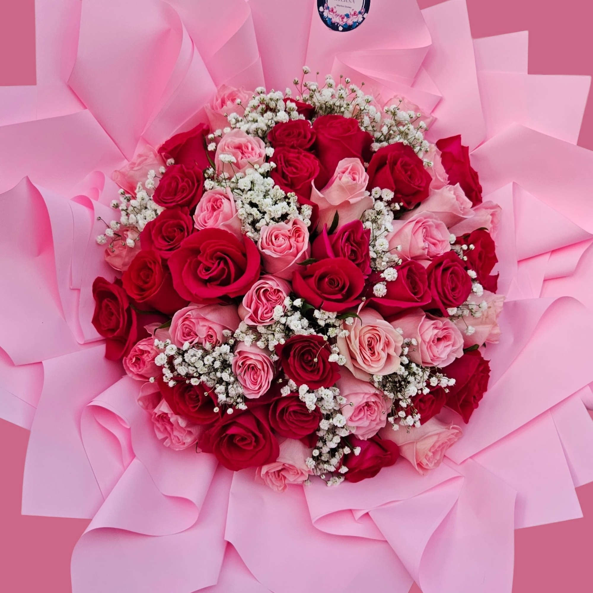 A lush, hand-tied bouquet of tightly packed pink and deep red roses
