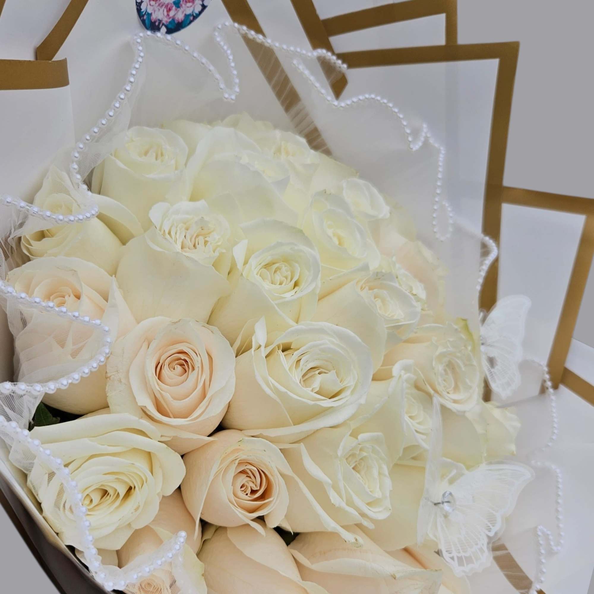 White  roses are tightly gathered into a classic rounded hand-tied bouquet