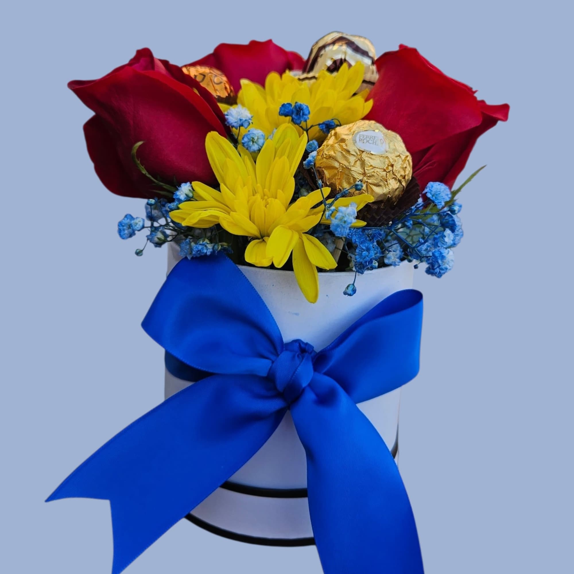 Deep red roses mingle with bright yellow daisies and tiny blue filler
