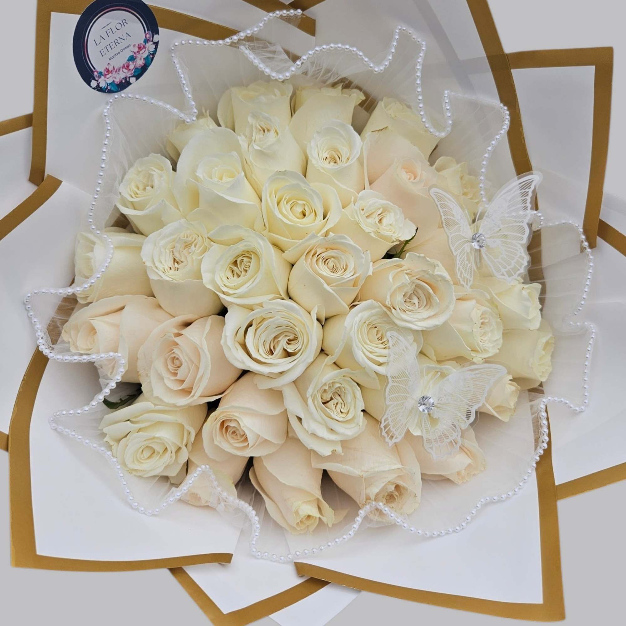 White  roses are tightly gathered into a classic rounded hand-tied bouquet